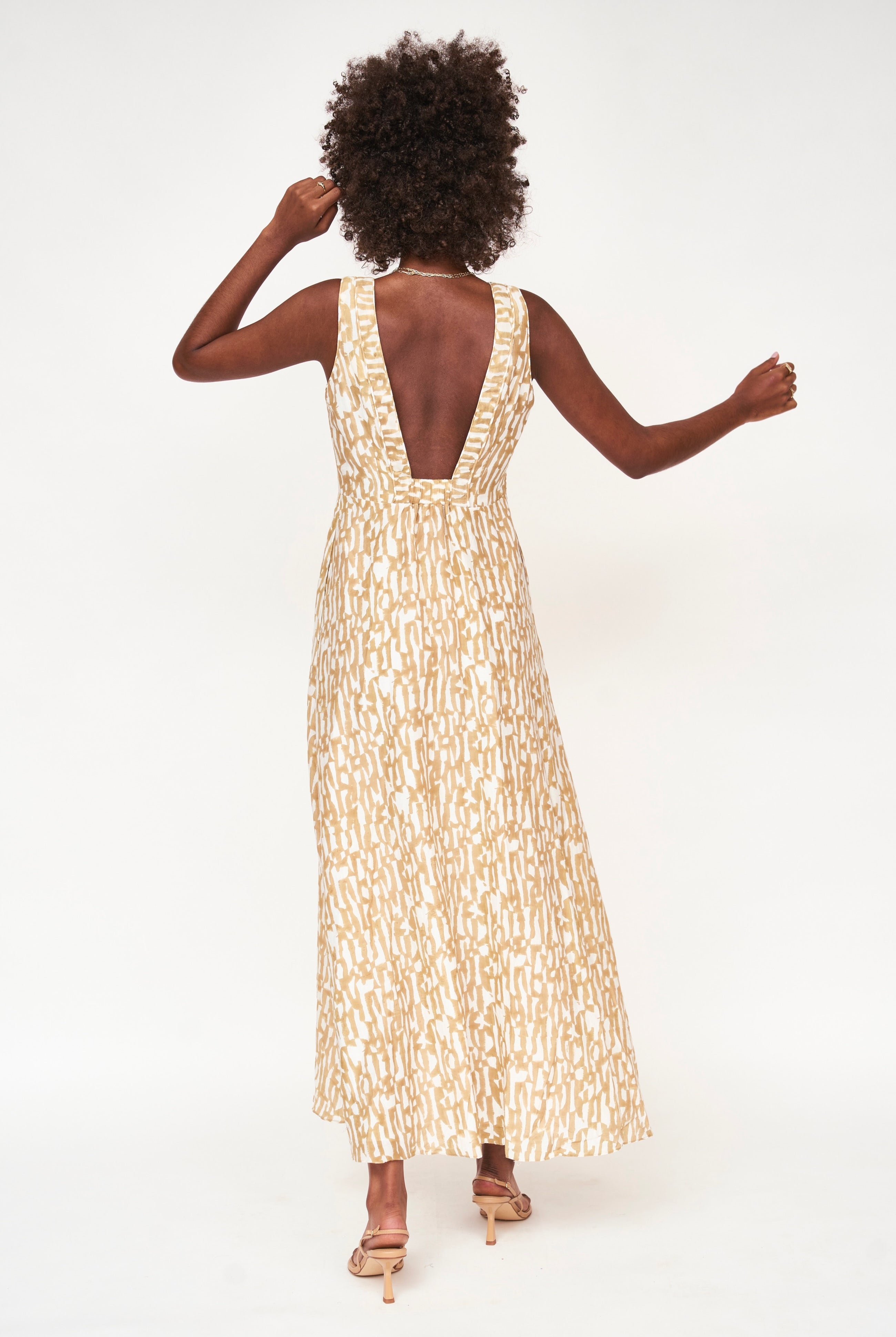 Girl wearing MIRTH women's v neck open back sleeveless cyprus long dress in driftwood brown print cotton silk