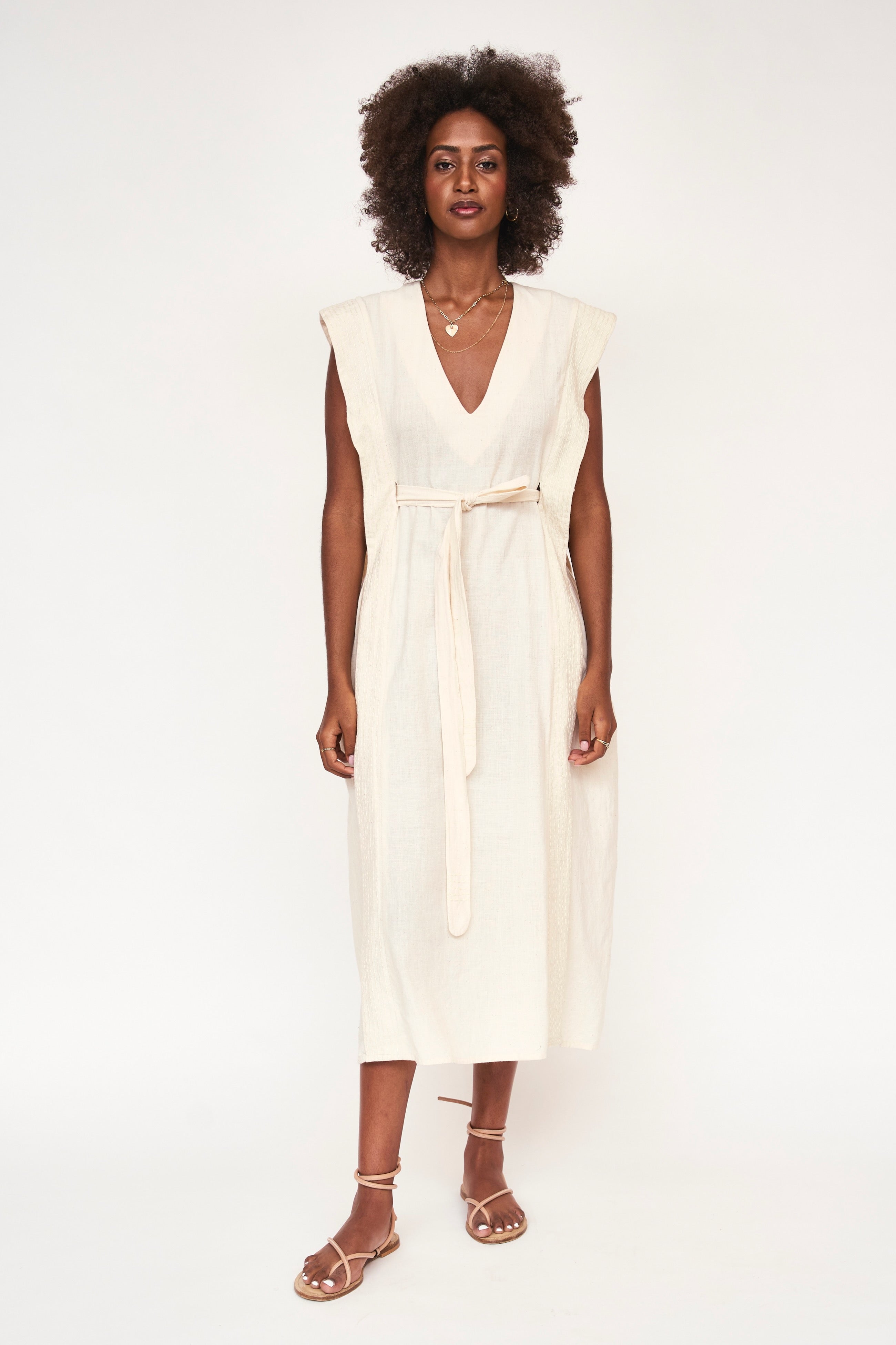 Girl wearing MIRTH women's v neck layered pintuck sleeveless long belted laguna dress in parchment cream cotton