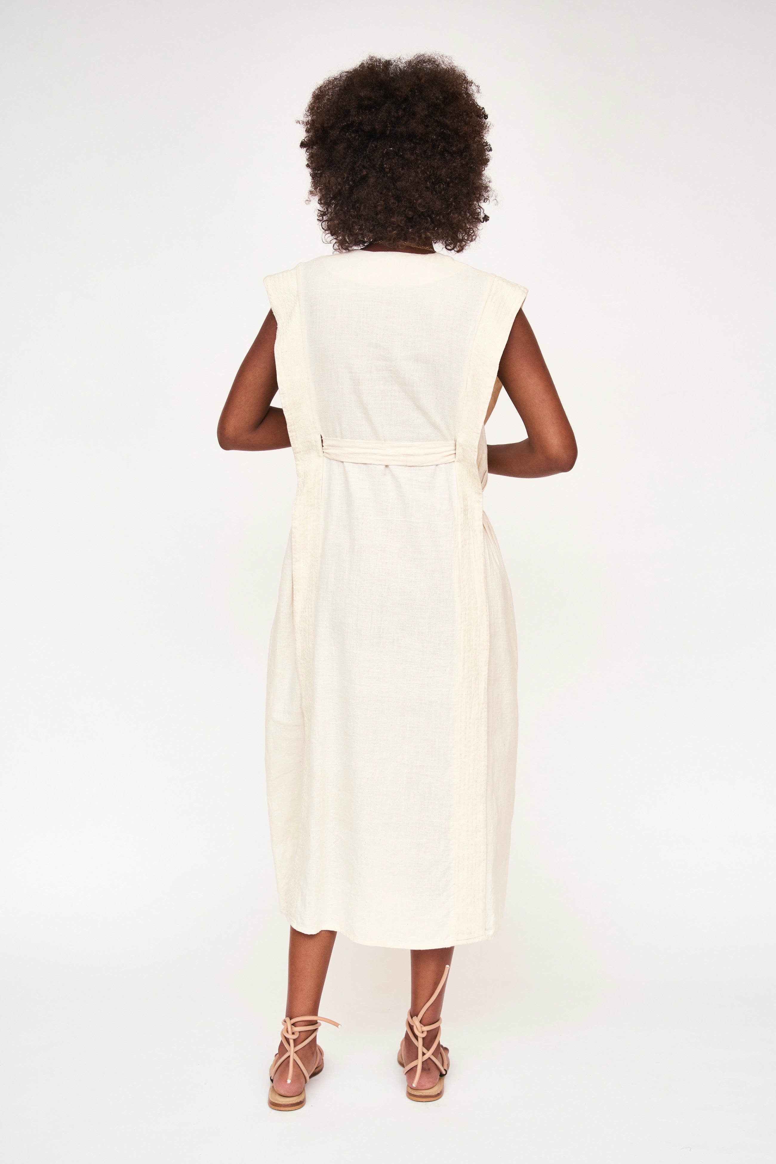 Girl wearing MIRTH women's v neck layered pintuck sleeveless long belted laguna dress in parchment cream cotton