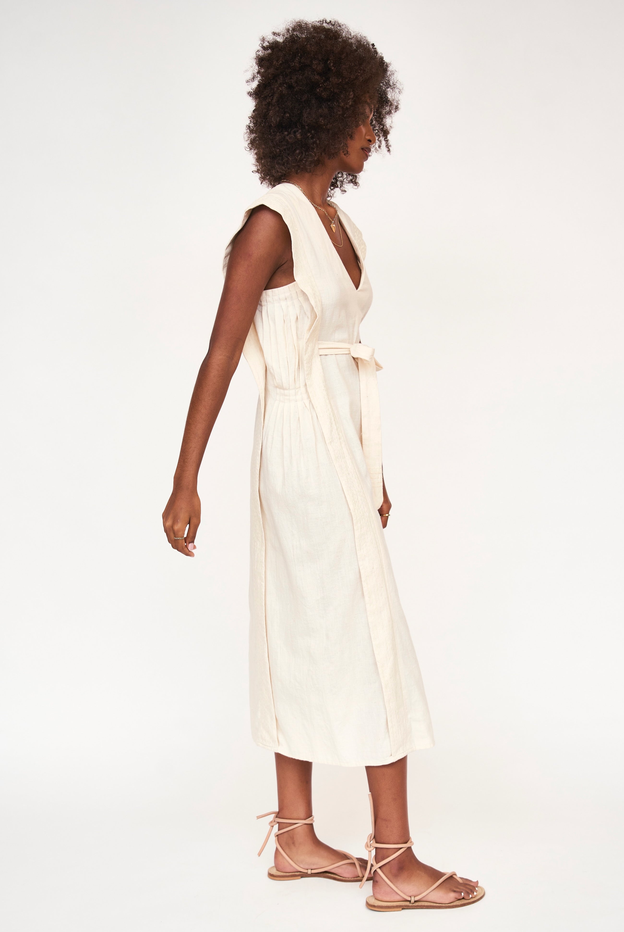 Girl wearing MIRTH women's v neck layered pintuck sleeveless long belted laguna dress in parchment cream cotton