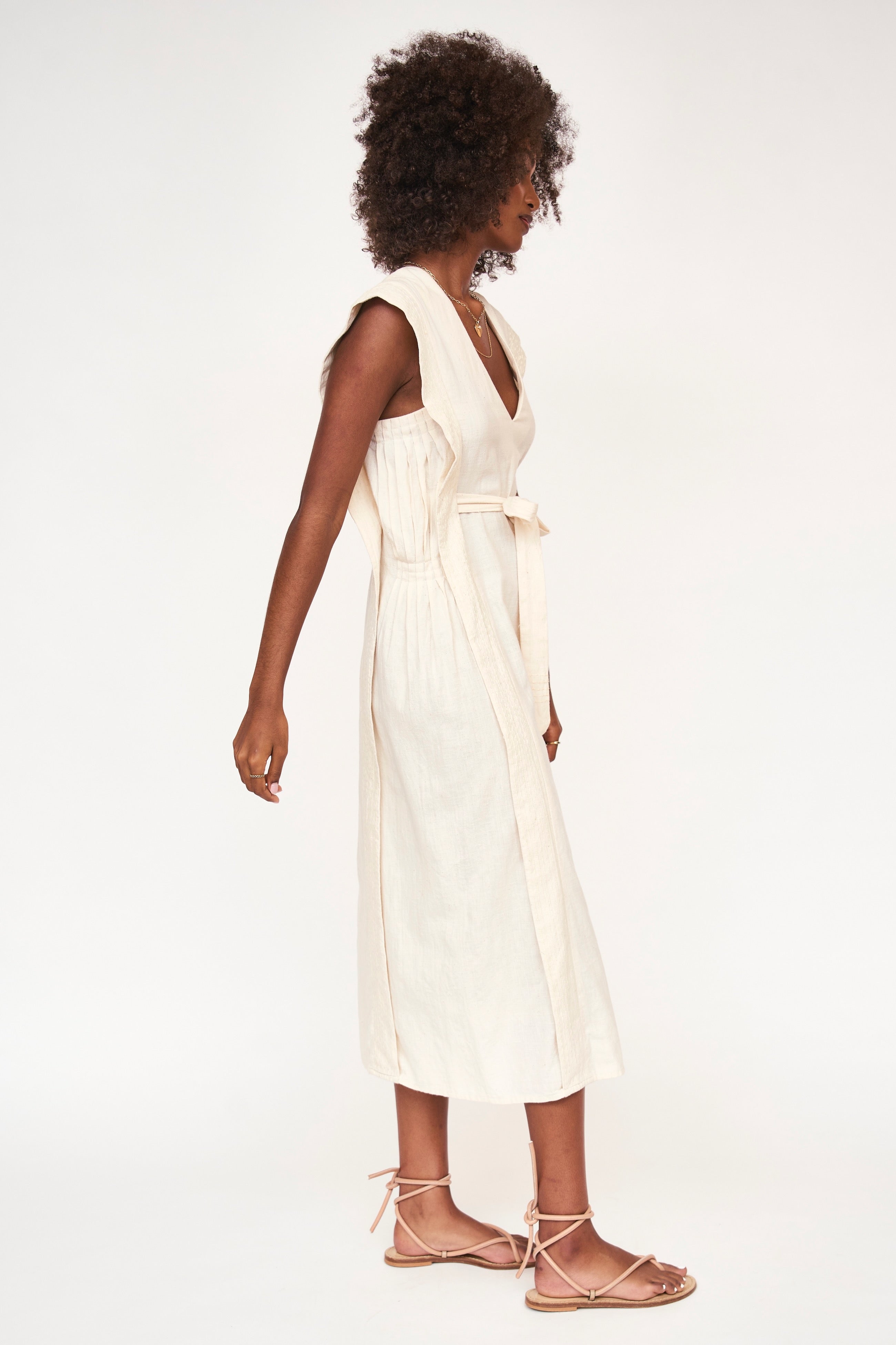 Girl wearing MIRTH women's v neck layered pintuck sleeveless long belted laguna dress in parchment cream cotton