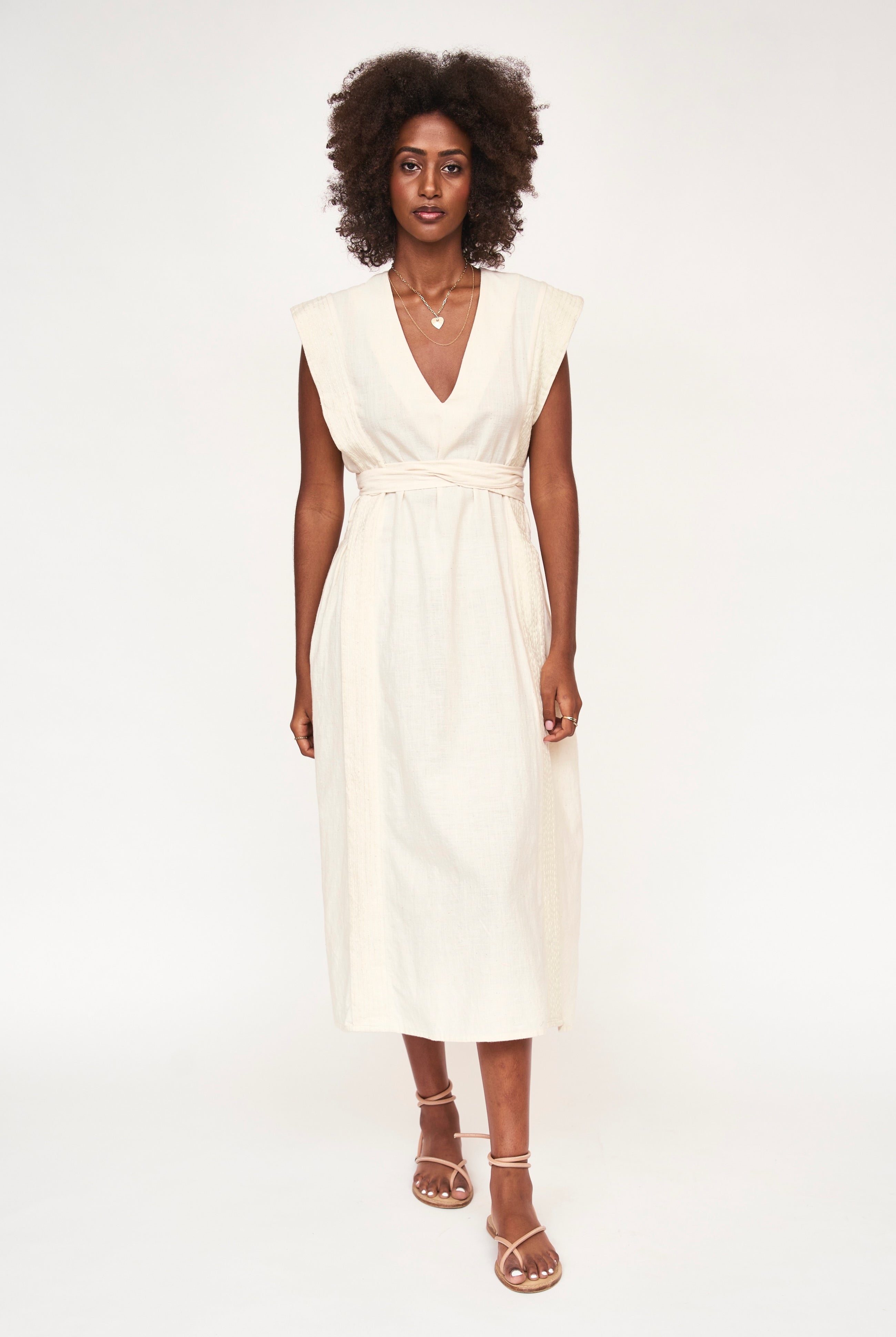 Girl wearing MIRTH women's v neck layered pintuck sleeveless long belted laguna dress in parchment cream cotton