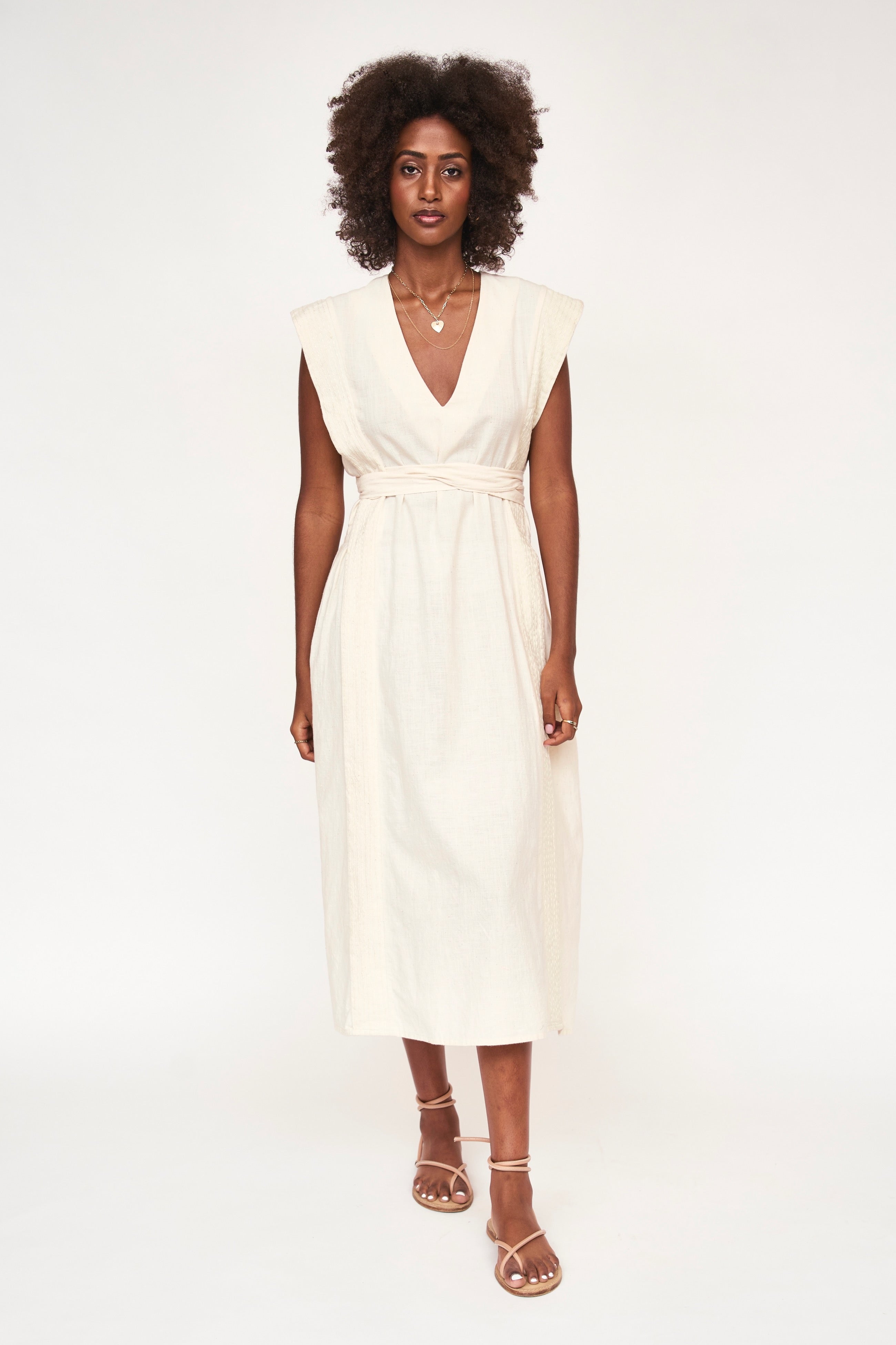 Girl wearing MIRTH women's v neck layered pintuck sleeveless long belted laguna dress in parchment cream cotton