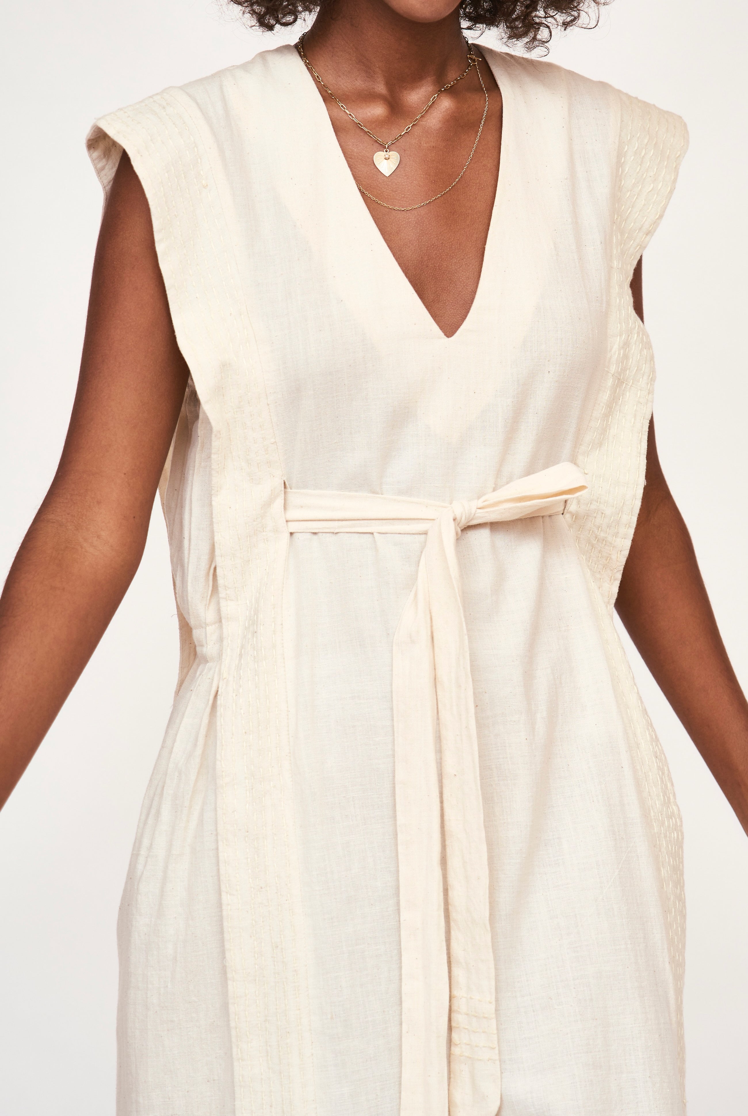 Girl wearing MIRTH women's v neck layered pintuck sleeveless long belted laguna dress in parchment cream cotton