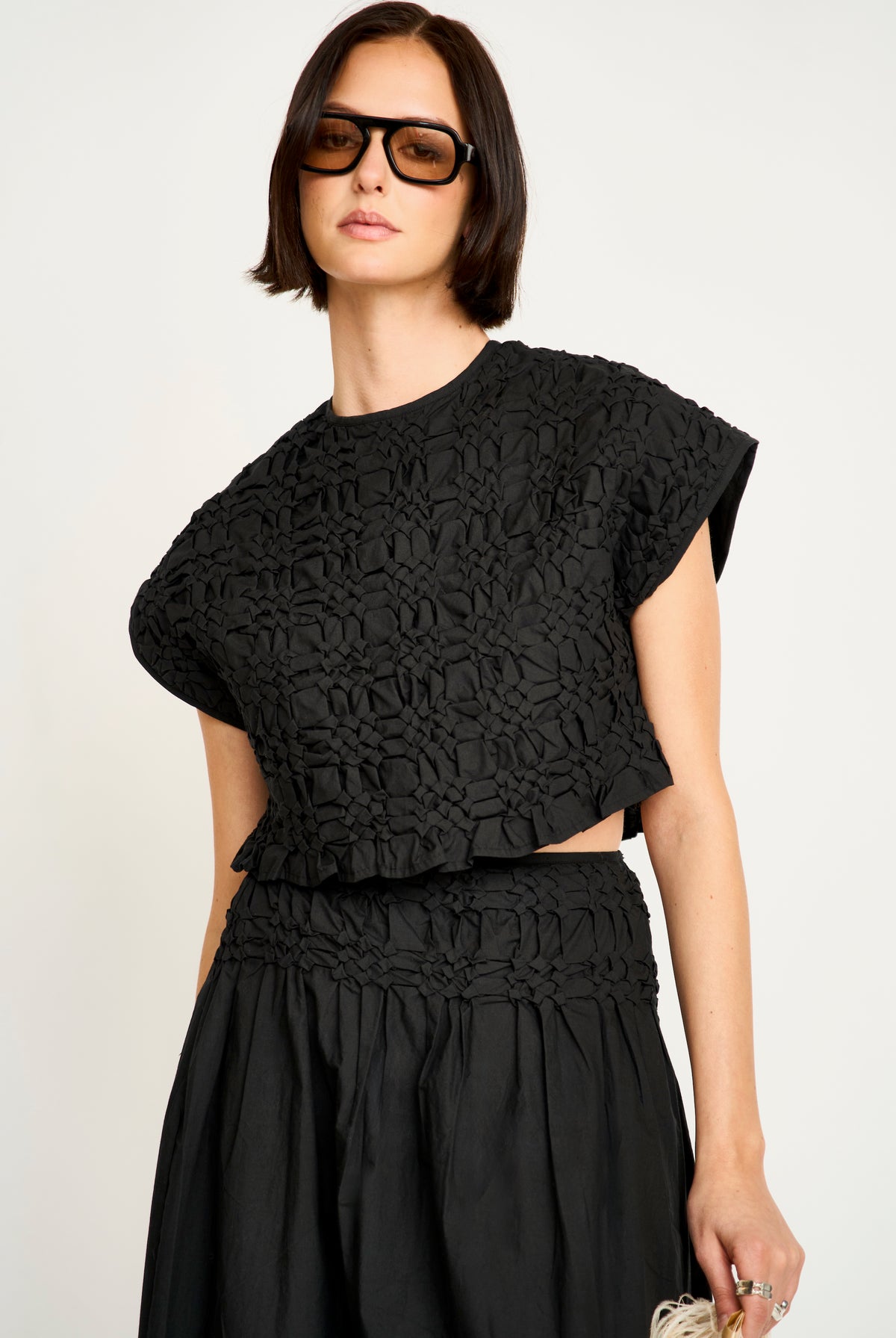 Woman wearing a black textured top and skirt set on a white background