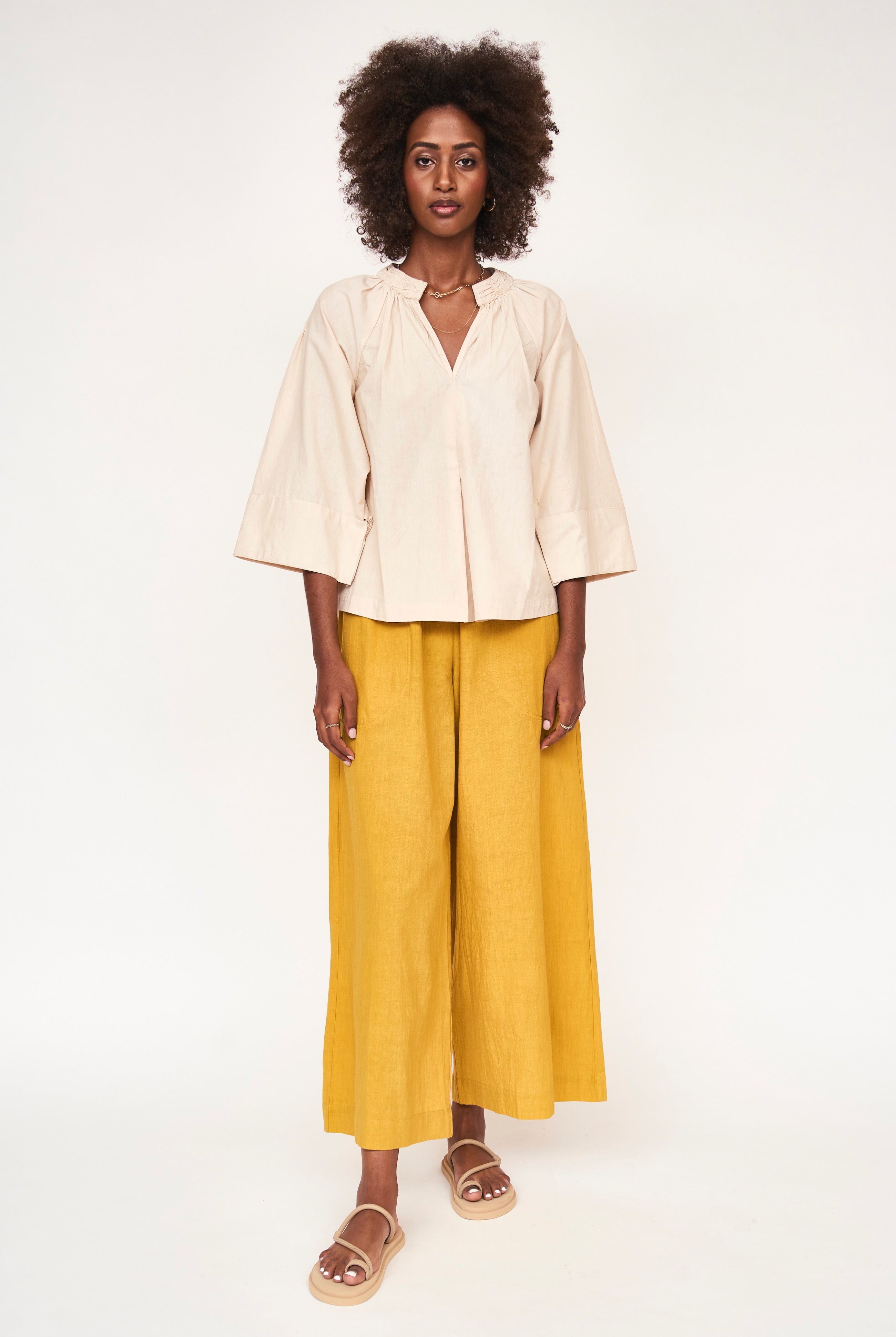 Girl wearing MIRTH women's v neck ruched collar three quarter sleeve palm springs top in parchment beige cotton poplin