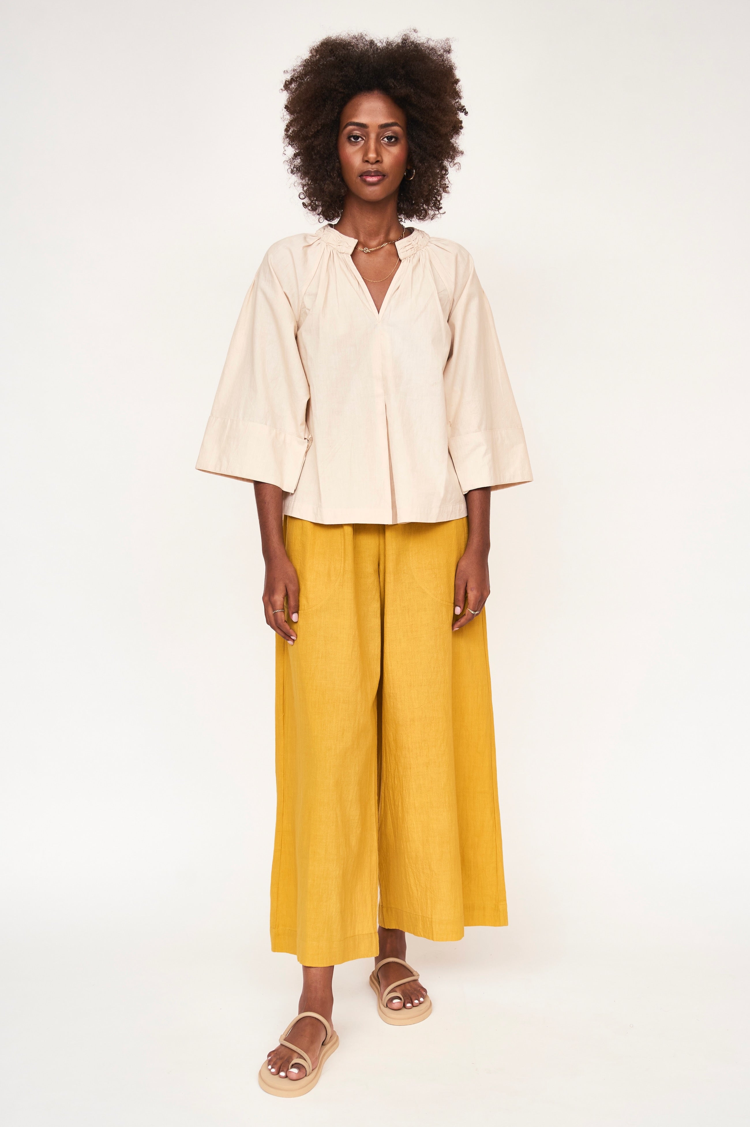 Girl wearing MIRTH women's v neck ruched collar three quarter sleeve palm springs top in parchment beige cotton poplin