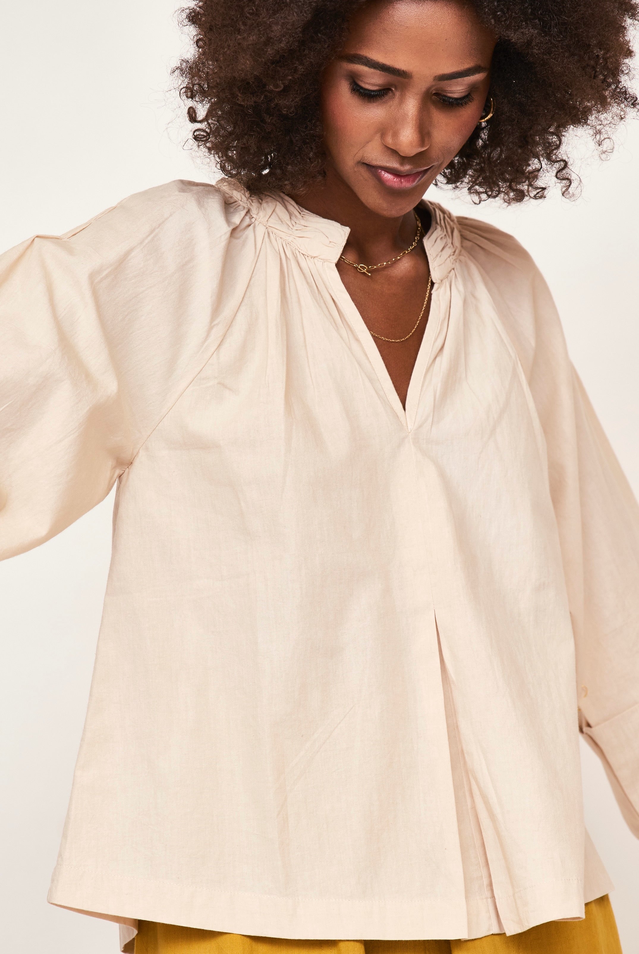 Girl wearing MIRTH women's v neck ruched collar three quarter sleeve palm springs top in parchment beige cotton poplin