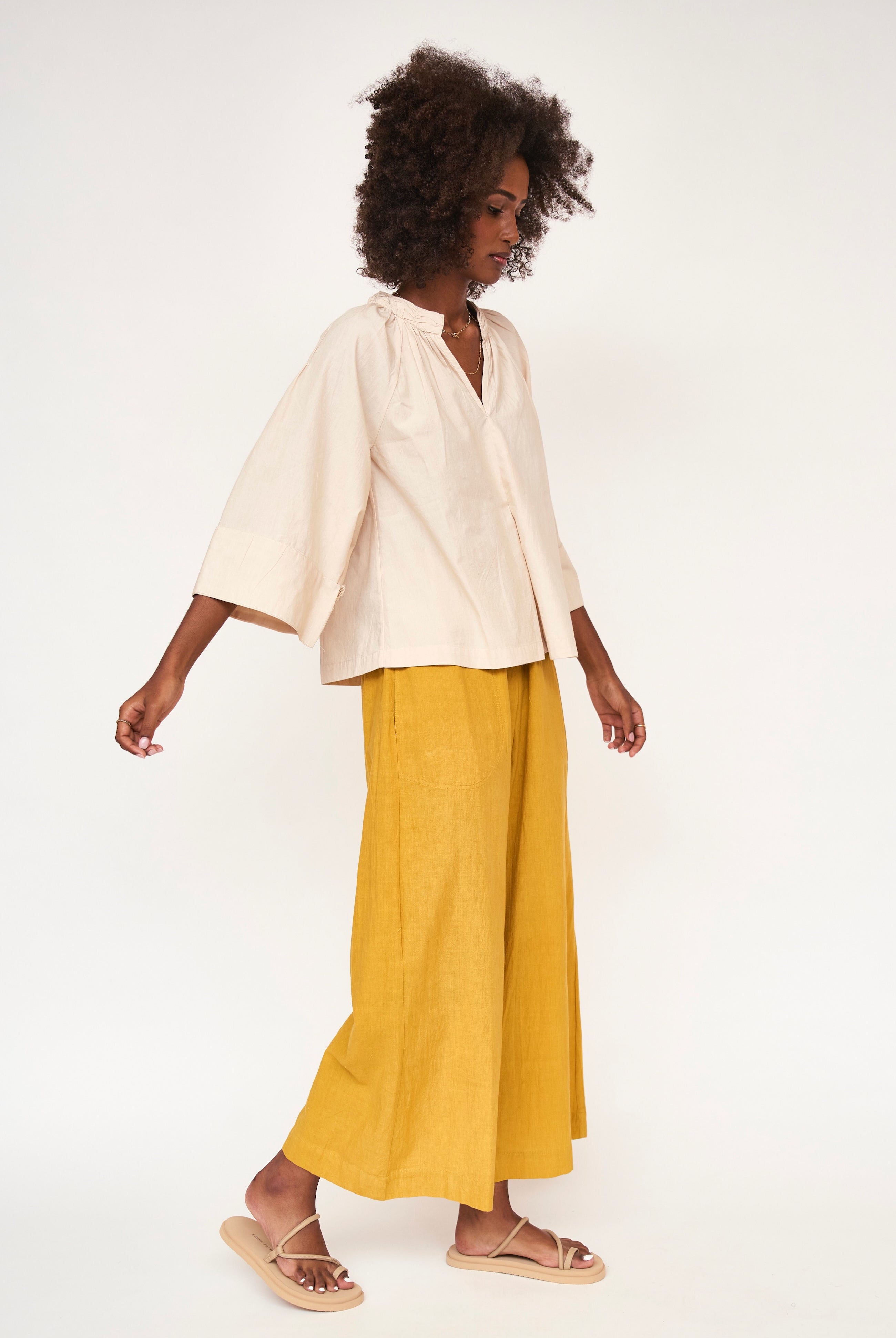 Girl wearing MIRTH women's v neck ruched collar three quarter sleeve palm springs top in parchment beige cotton poplin