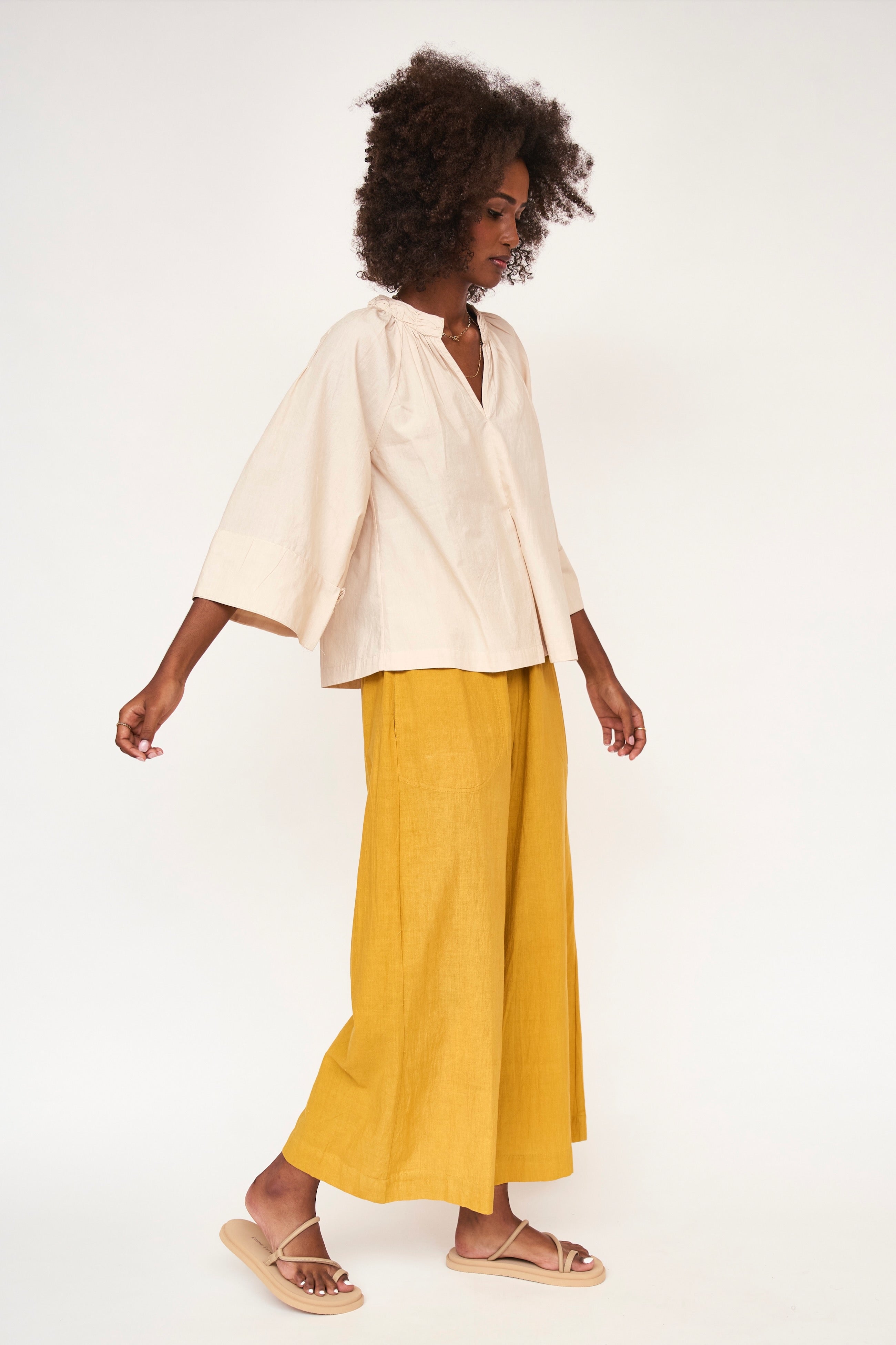 Girl wearing MIRTH women's v neck ruched collar three quarter sleeve palm springs top in parchment beige cotton poplin