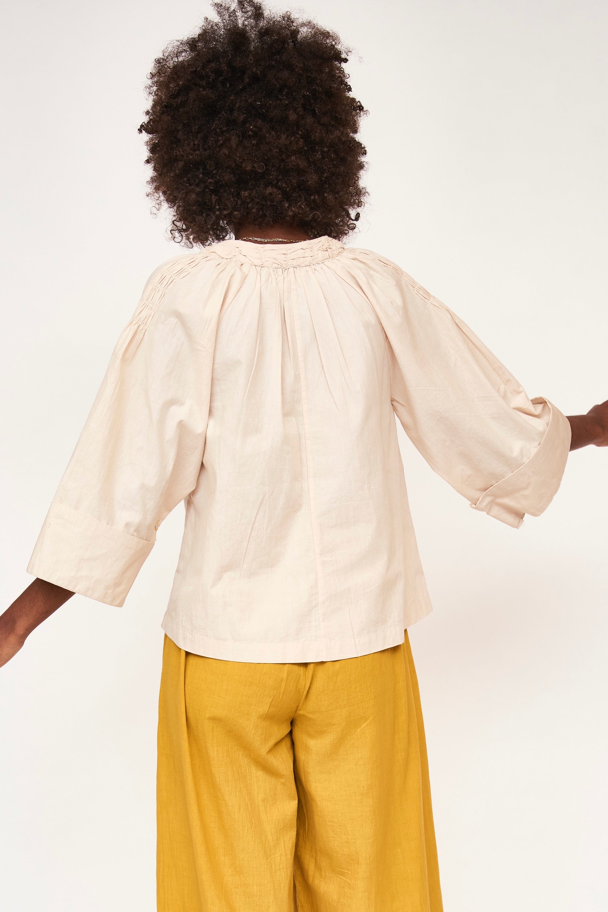 Girl wearing MIRTH women's v neck ruched collar three quarter sleeve palm springs top in parchment beige cotton poplin