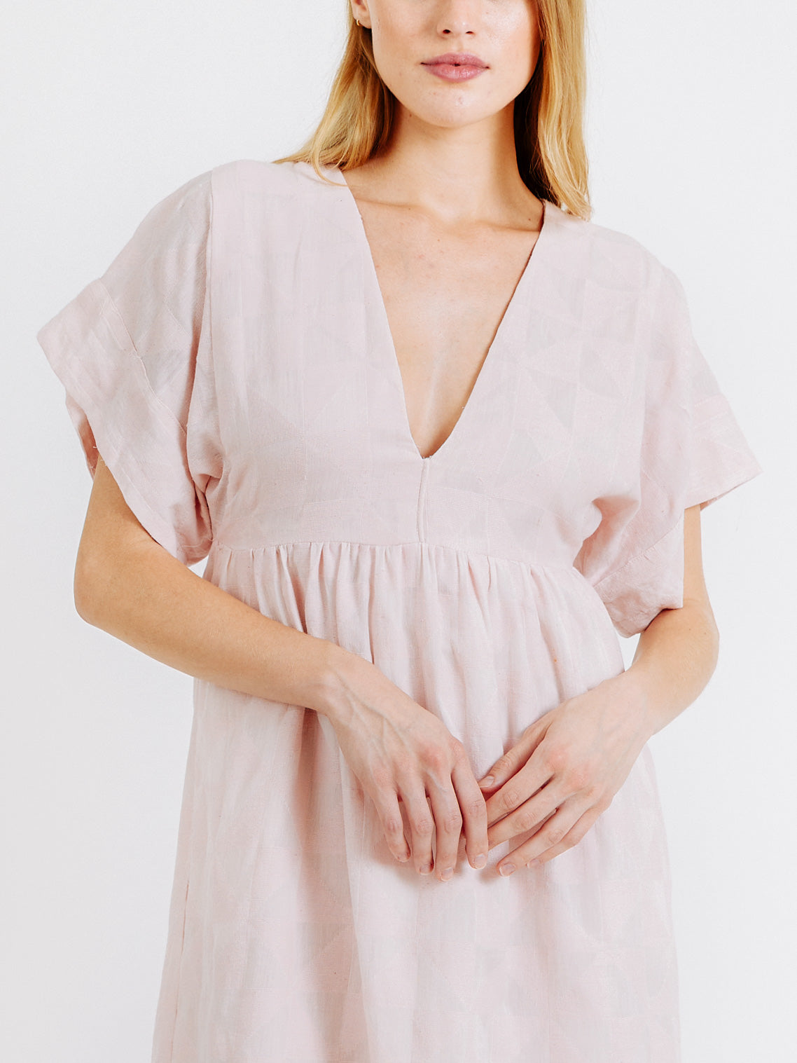 Girl wearing MIRTH women's v-neck short sonoma dress in handloomed light pink rosa cotton jacquard