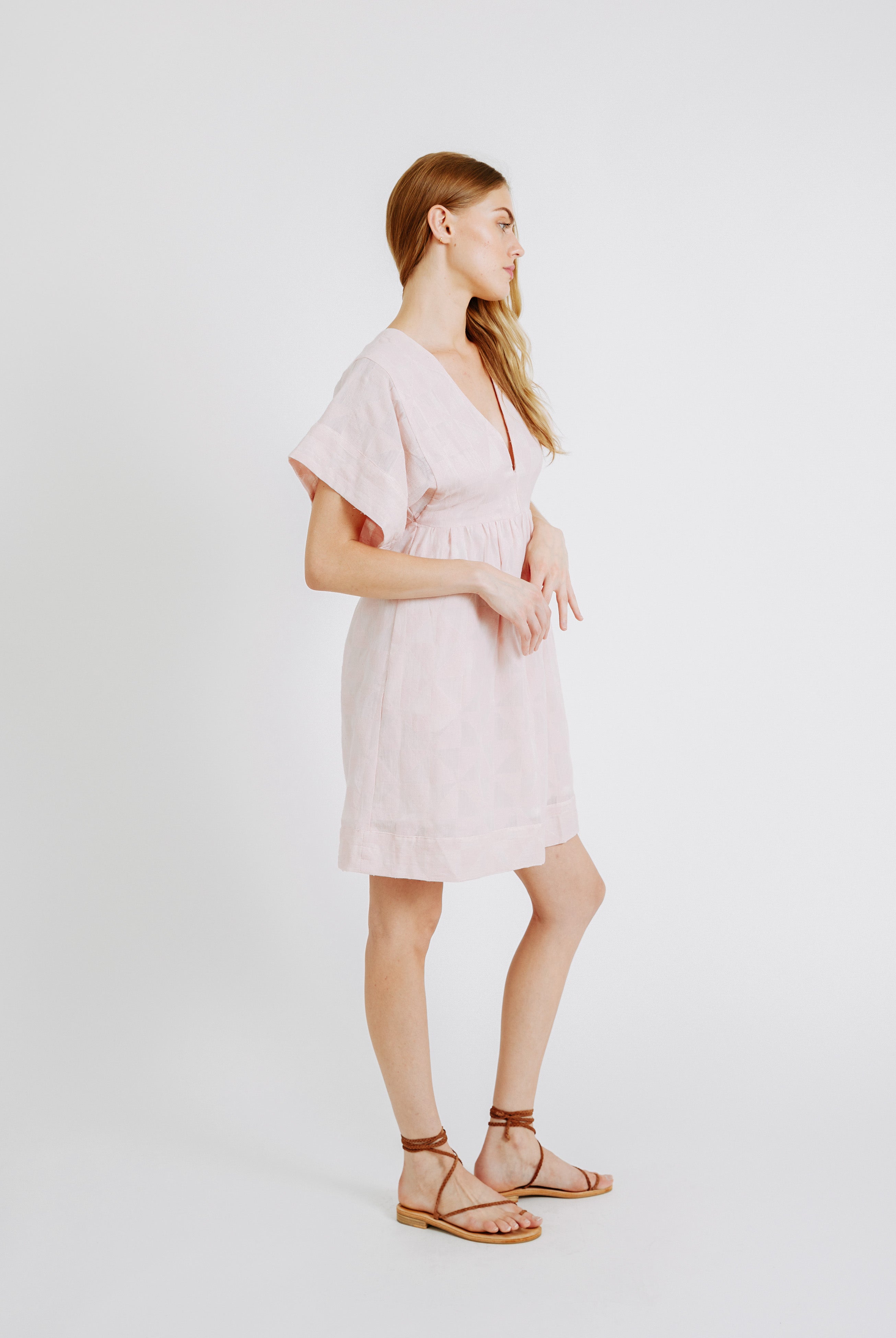 Girl wearing MIRTH women's v-neck short sonoma dress in handloomed light pink rosa cotton jacquard