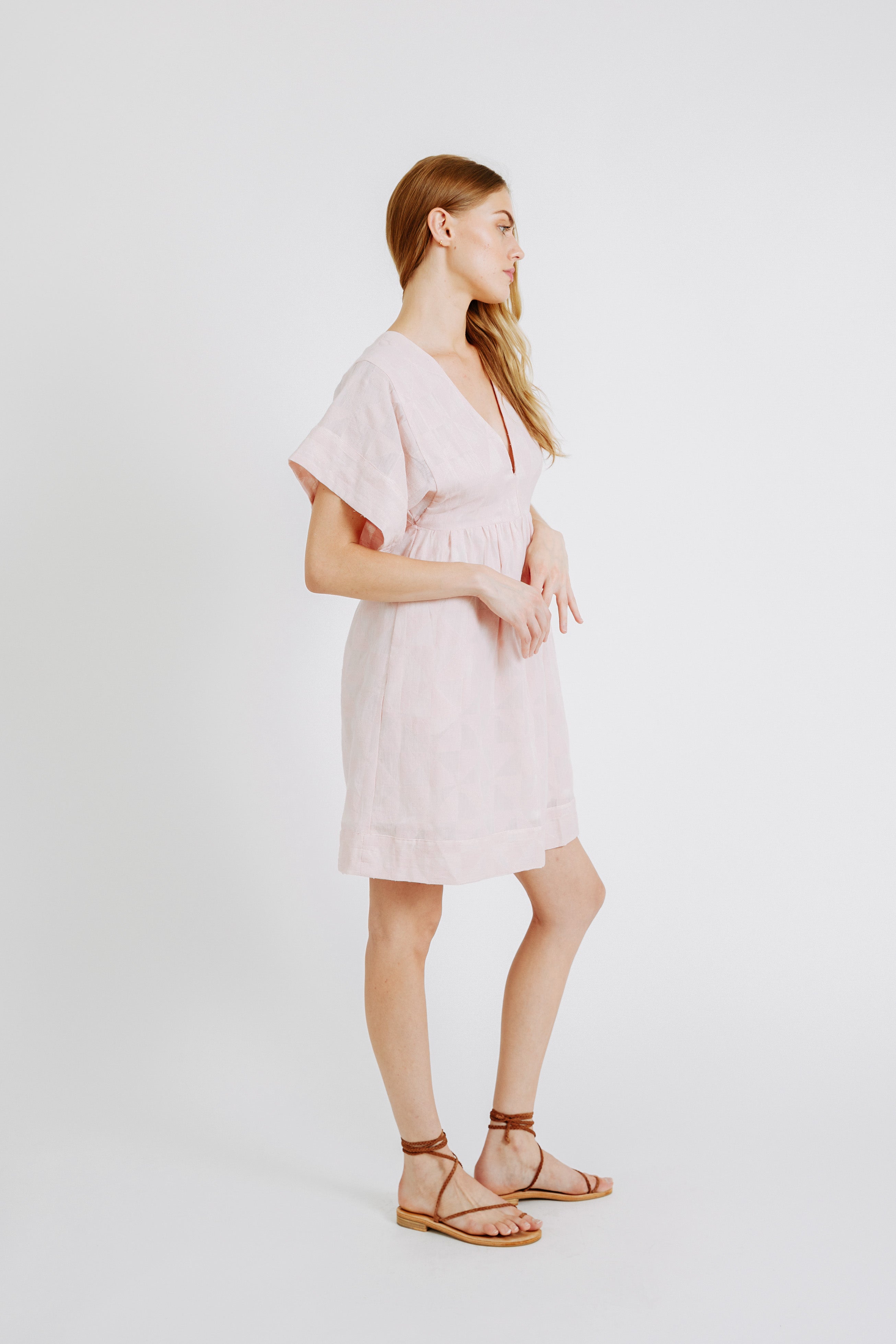 Girl wearing MIRTH women's v-neck short sonoma dress in handloomed light pink rosa cotton jacquard