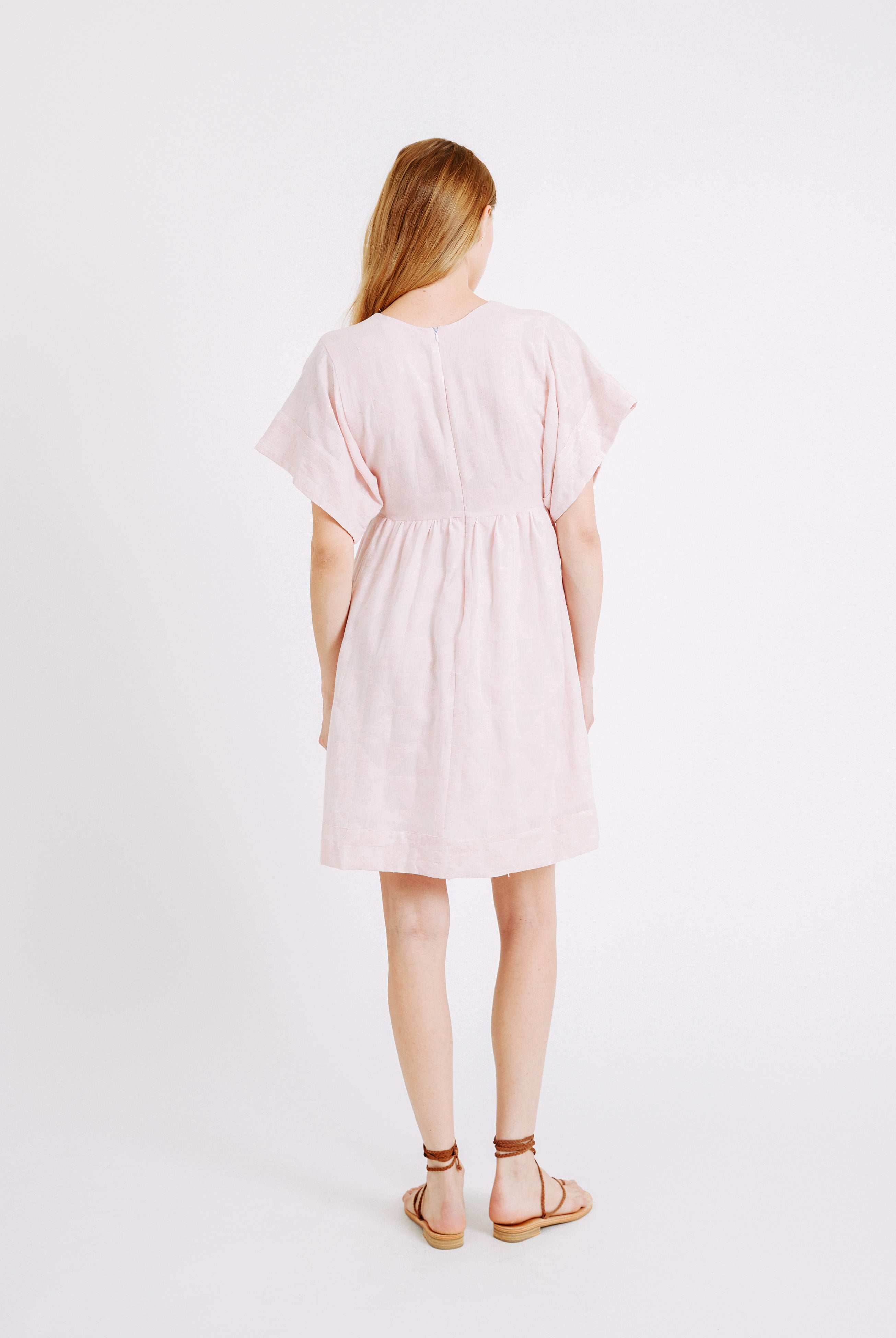 Girl wearing MIRTH women's v-neck short sonoma dress in handloomed light pink rosa cotton jacquard