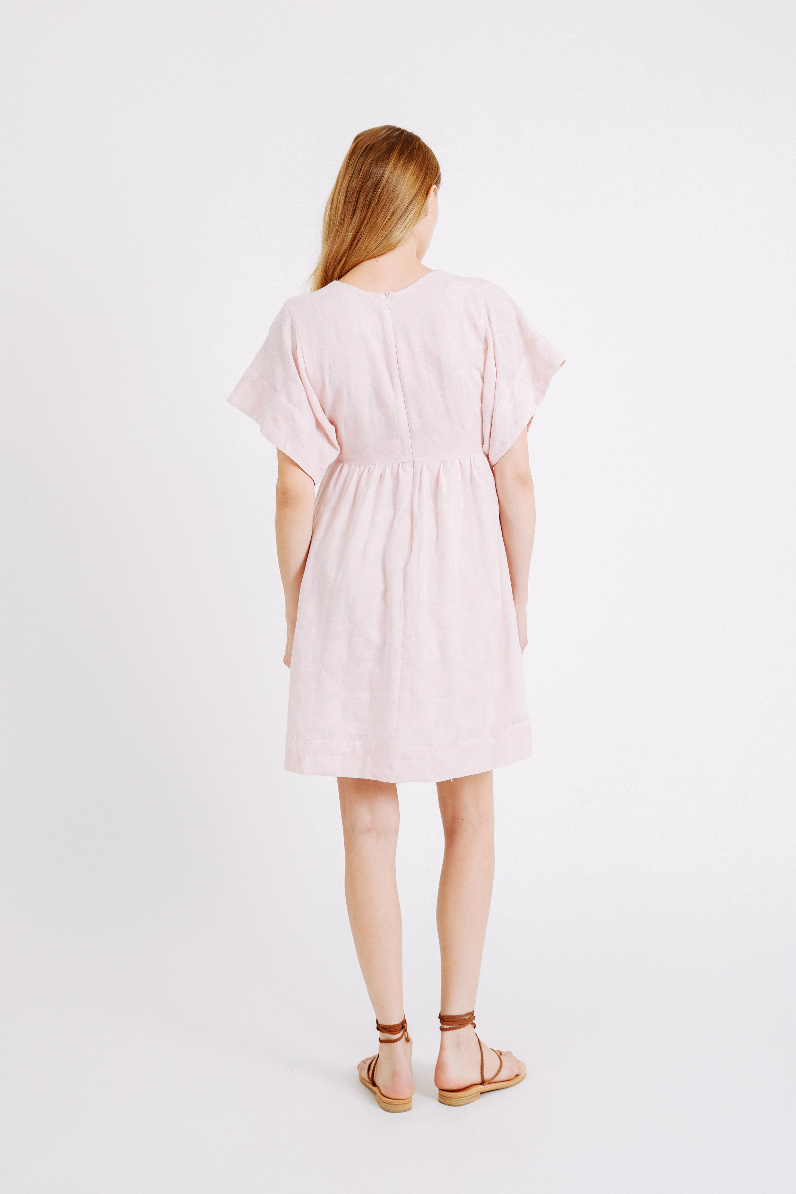 Girl wearing MIRTH women's v-neck short sonoma dress in handloomed light pink rosa cotton jacquard