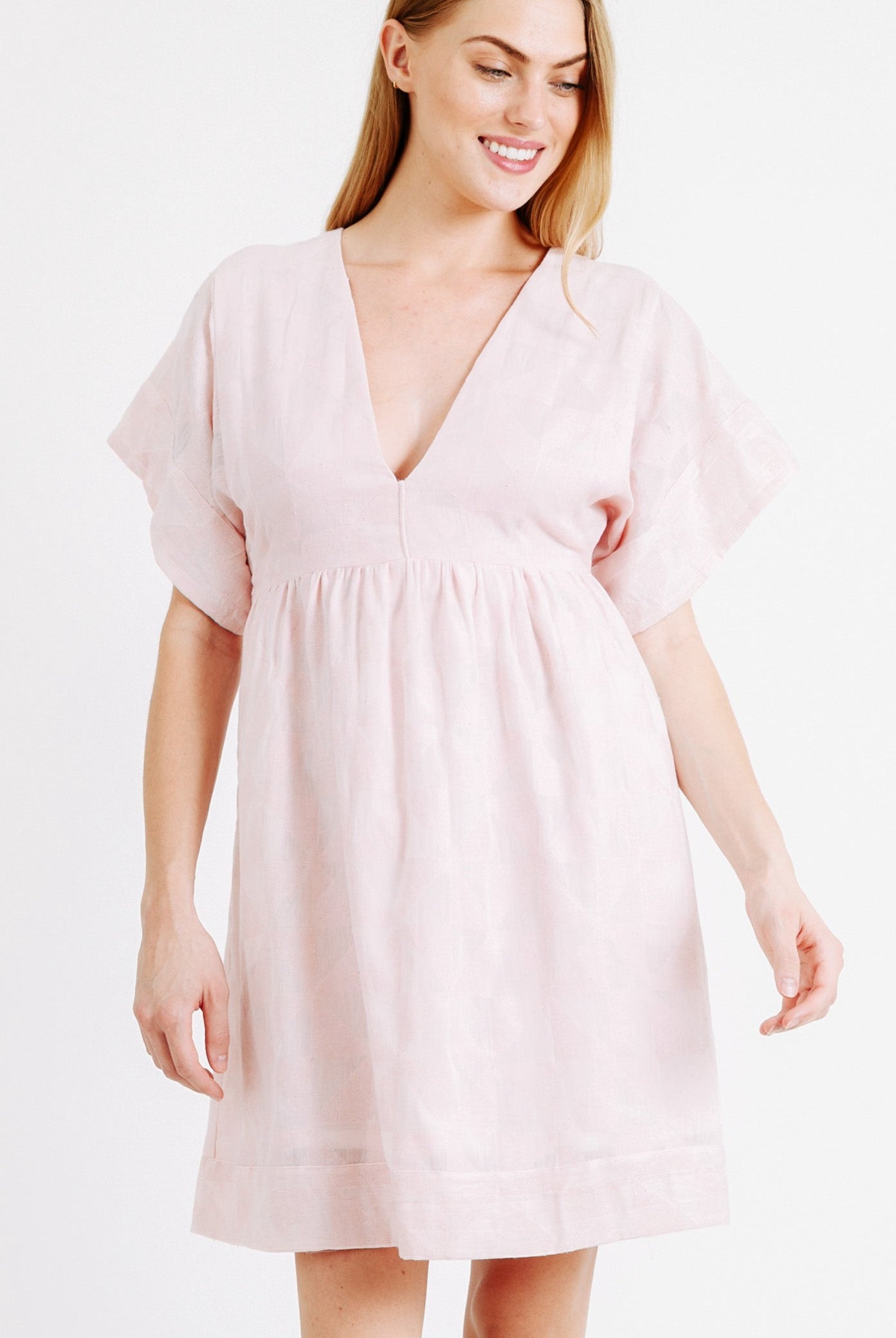 Girl wearing MIRTH women's v-neck short sonoma dress in handloomed light pink rosa cotton jacquard