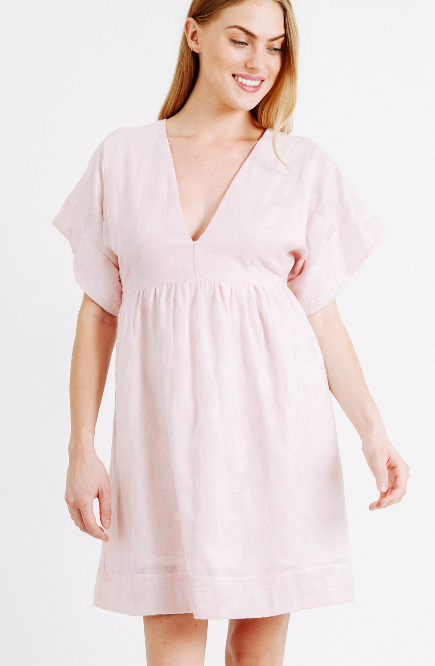 Girl wearing MIRTH women's v-neck short sonoma dress in handloomed light pink rosa cotton jacquard