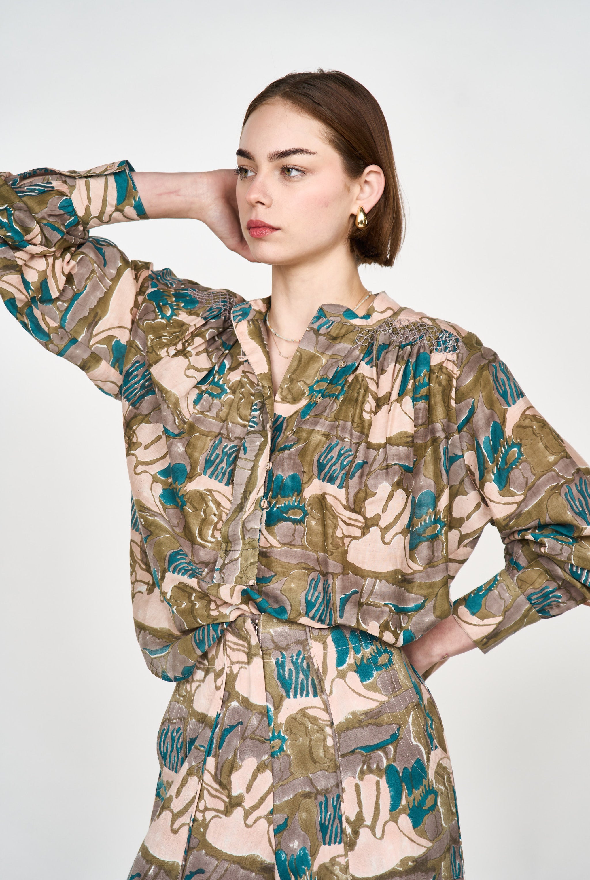 Girl wearing MIRTH women's button up smocked lightweight florence blouse in brown moss reef print cotton