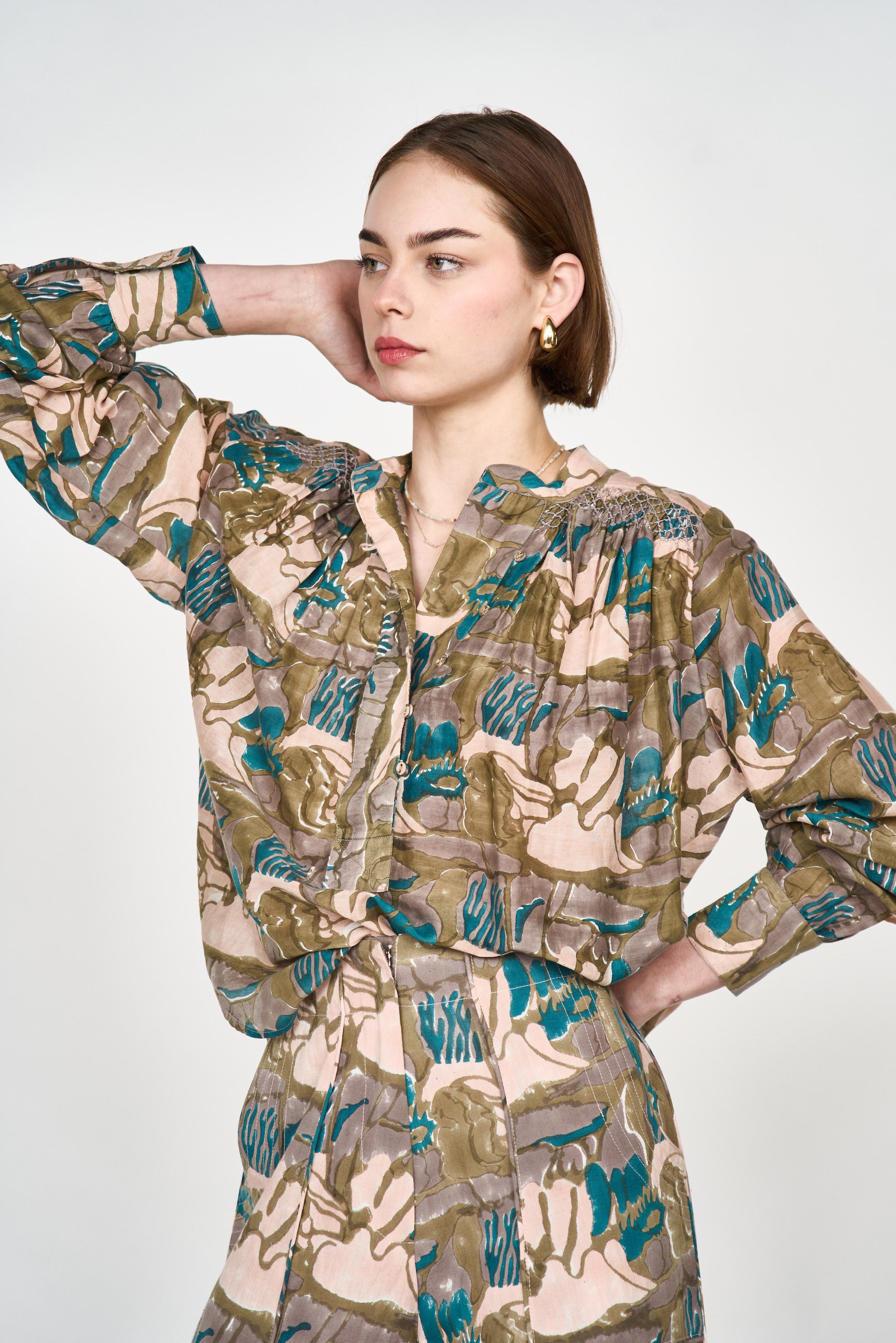 Girl wearing MIRTH women's button up smocked lightweight florence blouse in brown moss reef print cotton