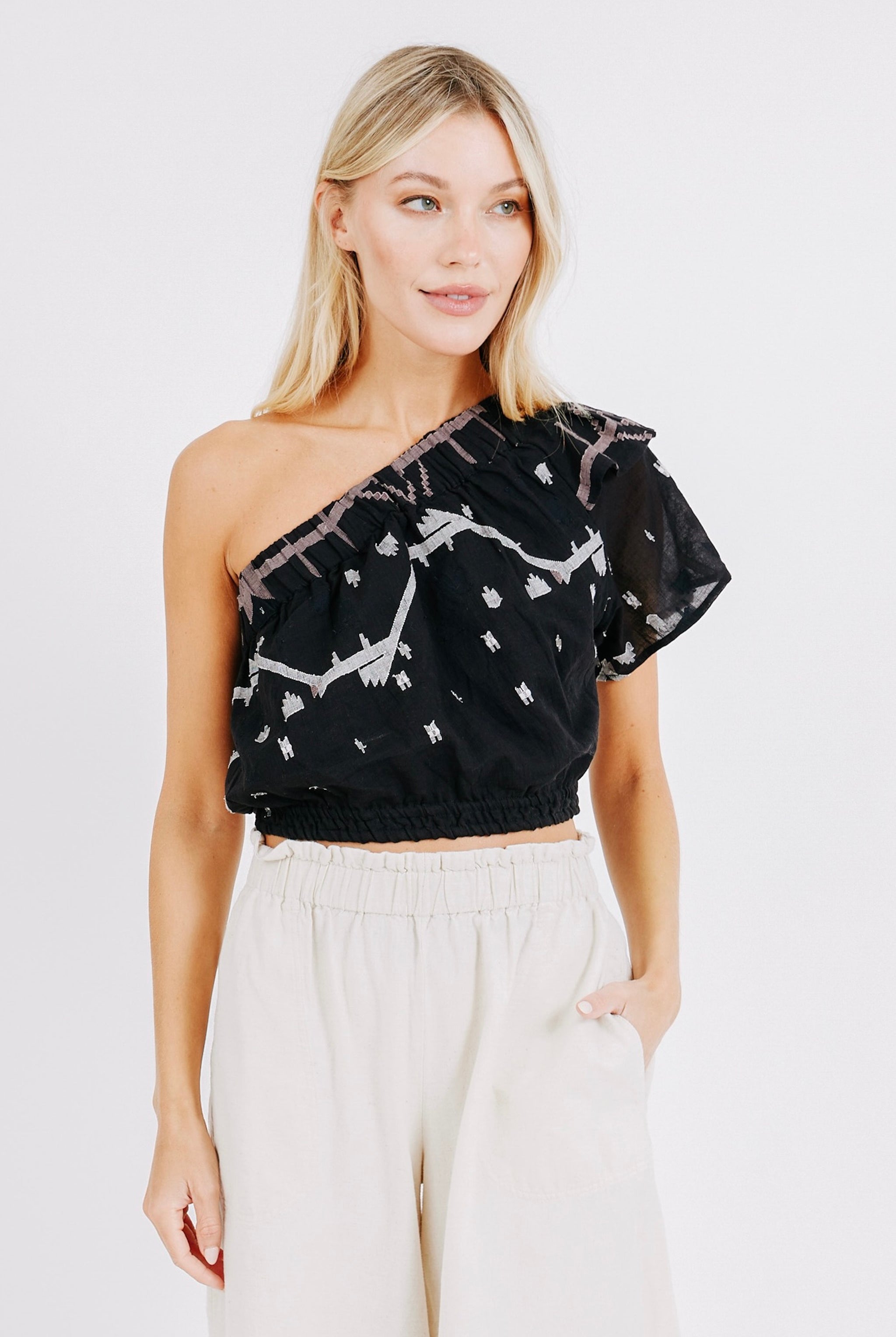 Girl wearing MIRTH women's cropped one shoulder paros top set in handloomed black carnival jamdani