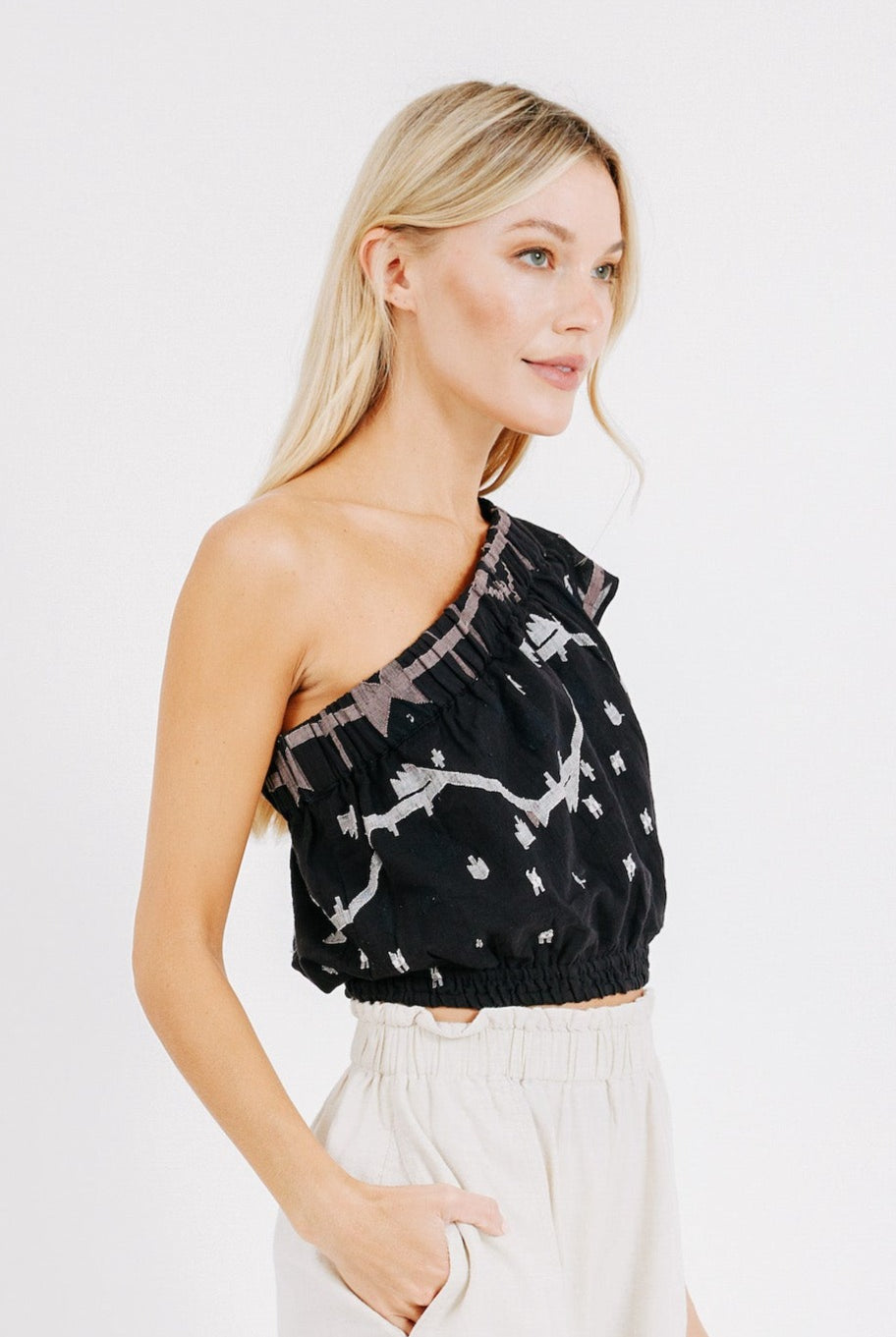 Girl wearing MIRTH women's cropped one shoulder paros top set in handloomed black carnival jamdani