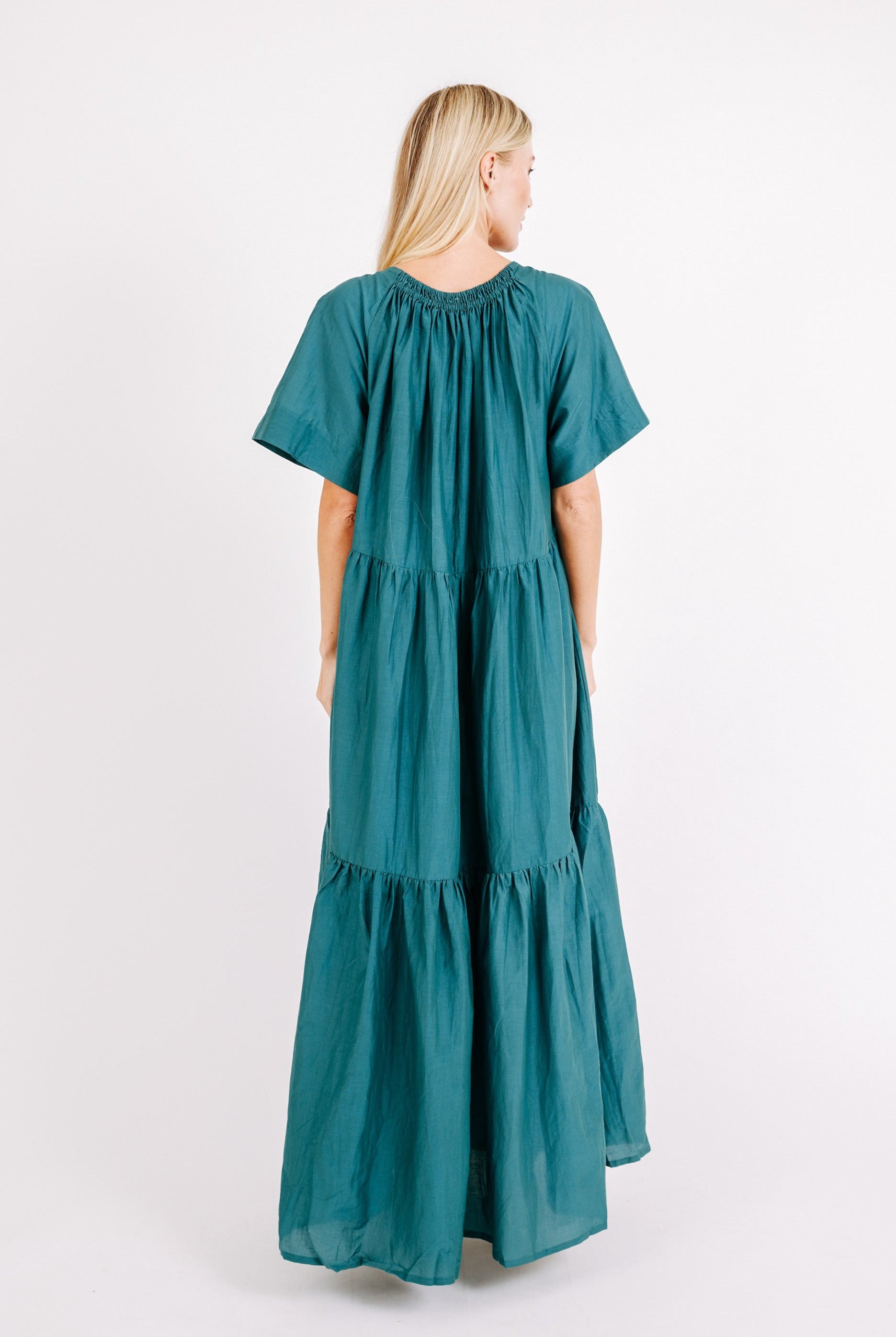 Girl wearing MIRTH women's long tiered gathered short sleeve vienna maxi dress in spruce green cotton silk with tie belt