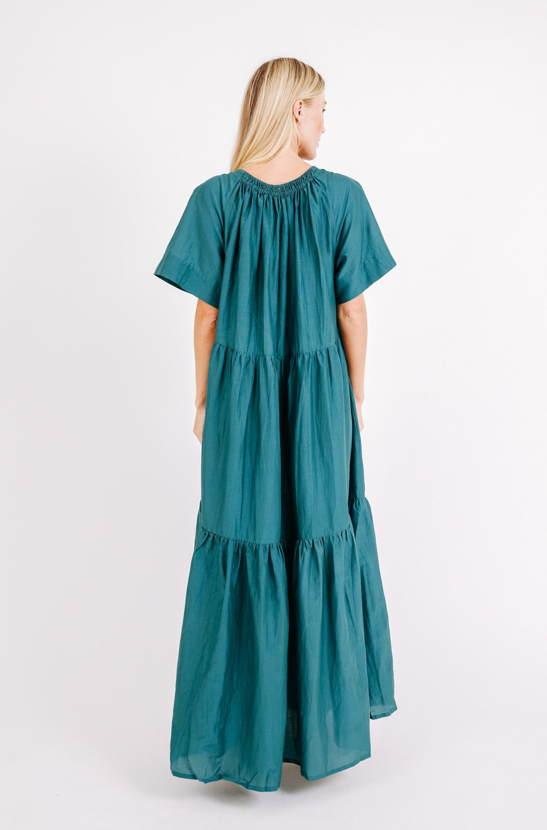 Girl wearing MIRTH women's long tiered gathered short sleeve vienna maxi dress in spruce green cotton silk with tie belt