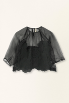Black sheer blouse on a beige background