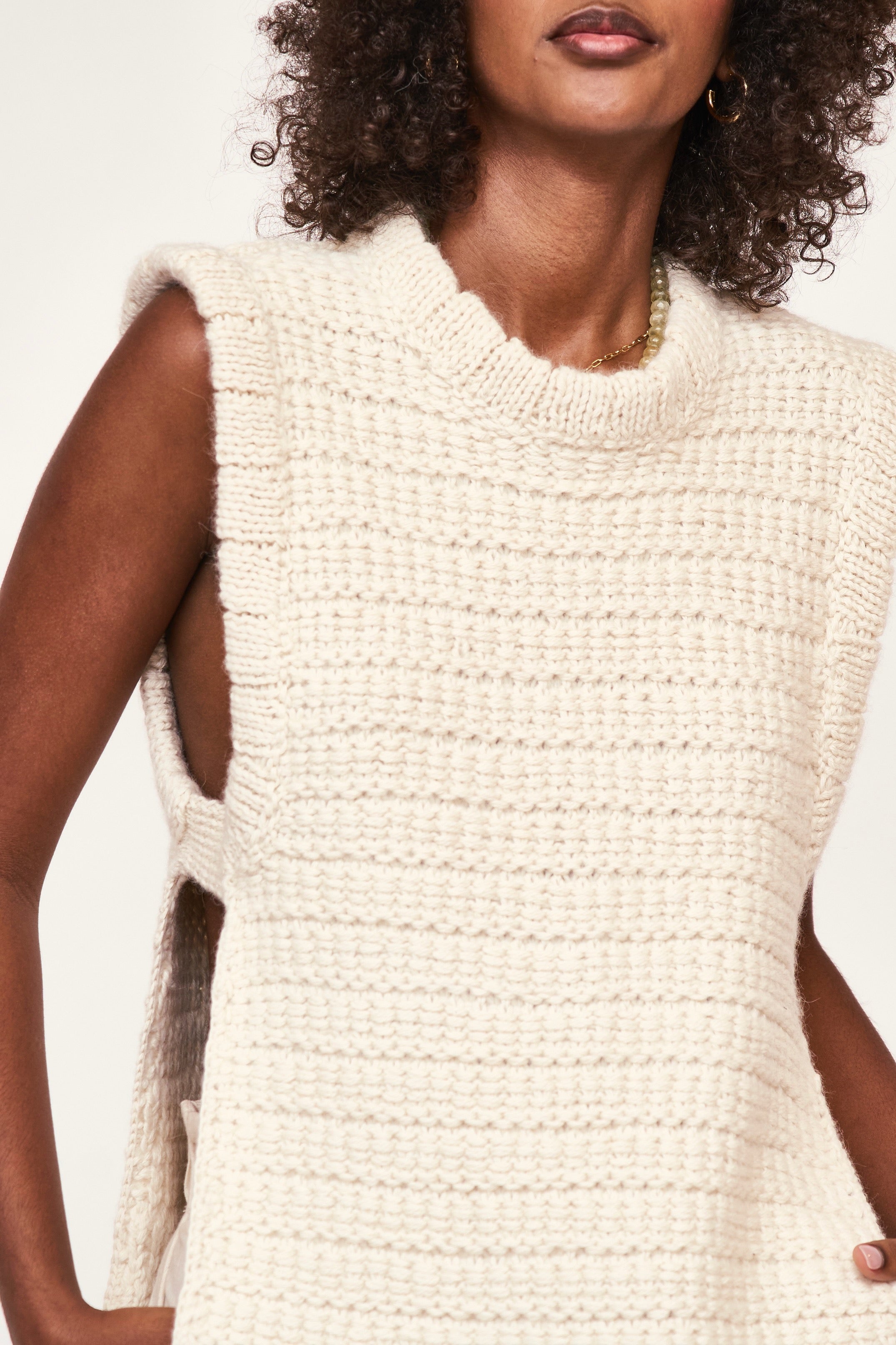 Girl wearing MIRTH women's sleeveless carmel open side knit sweater vest in snow white alpaca wool