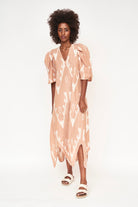 Girl wearing MIRTH women's puff sleeve v neck scallop hem cassis long dress in conch ikat peach cotton