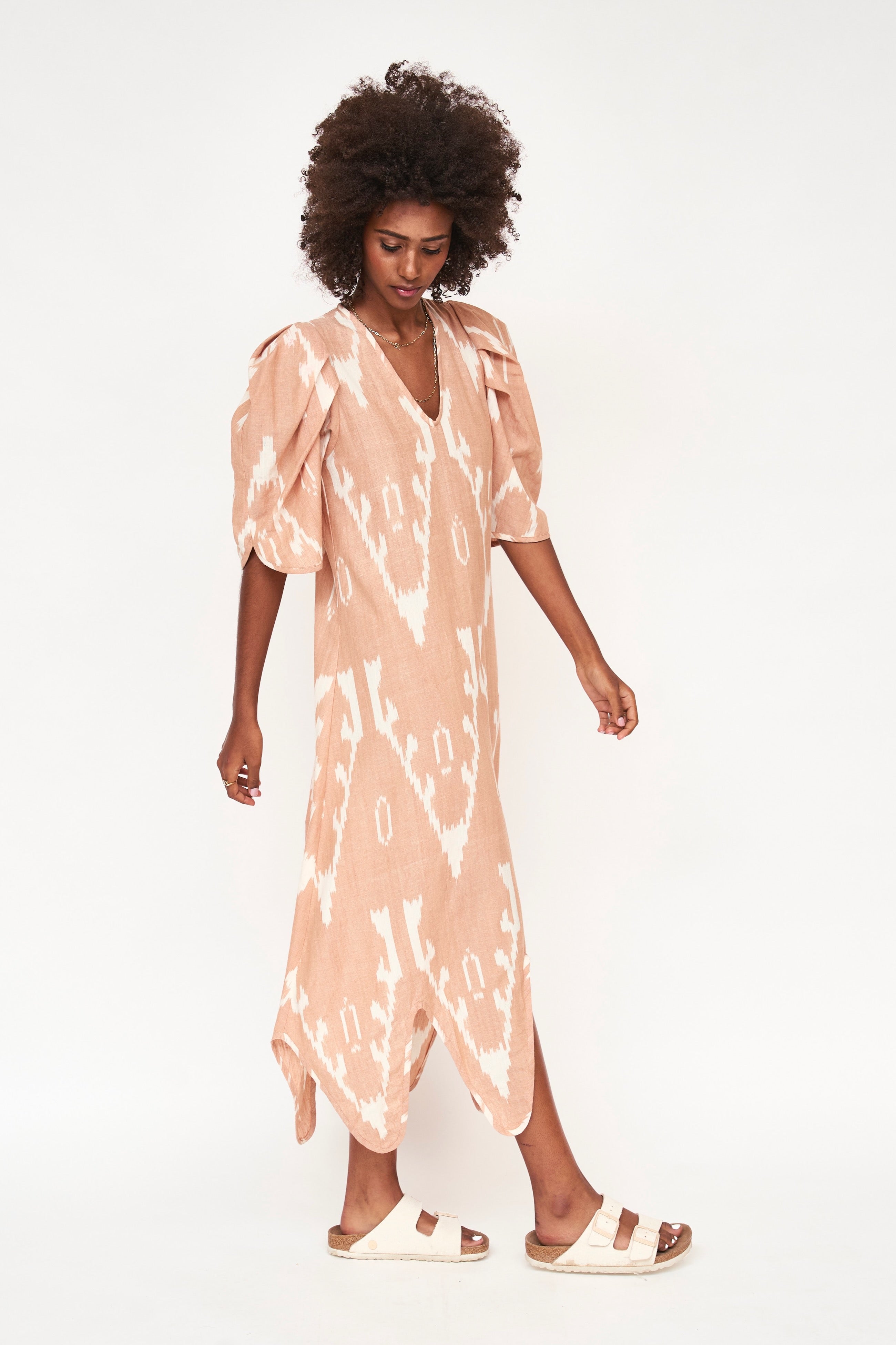 Girl wearing MIRTH women's puff sleeve v neck scallop hem cassis long dress in conch ikat peach cotton