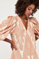 Girl wearing MIRTH women's puff sleeve v neck scallop hem cassis long dress in conch ikat peach cotton