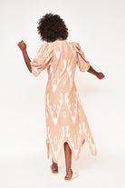 Girl wearing MIRTH women's puff sleeve v neck scallop hem cassis long dress in conch ikat peach cotton