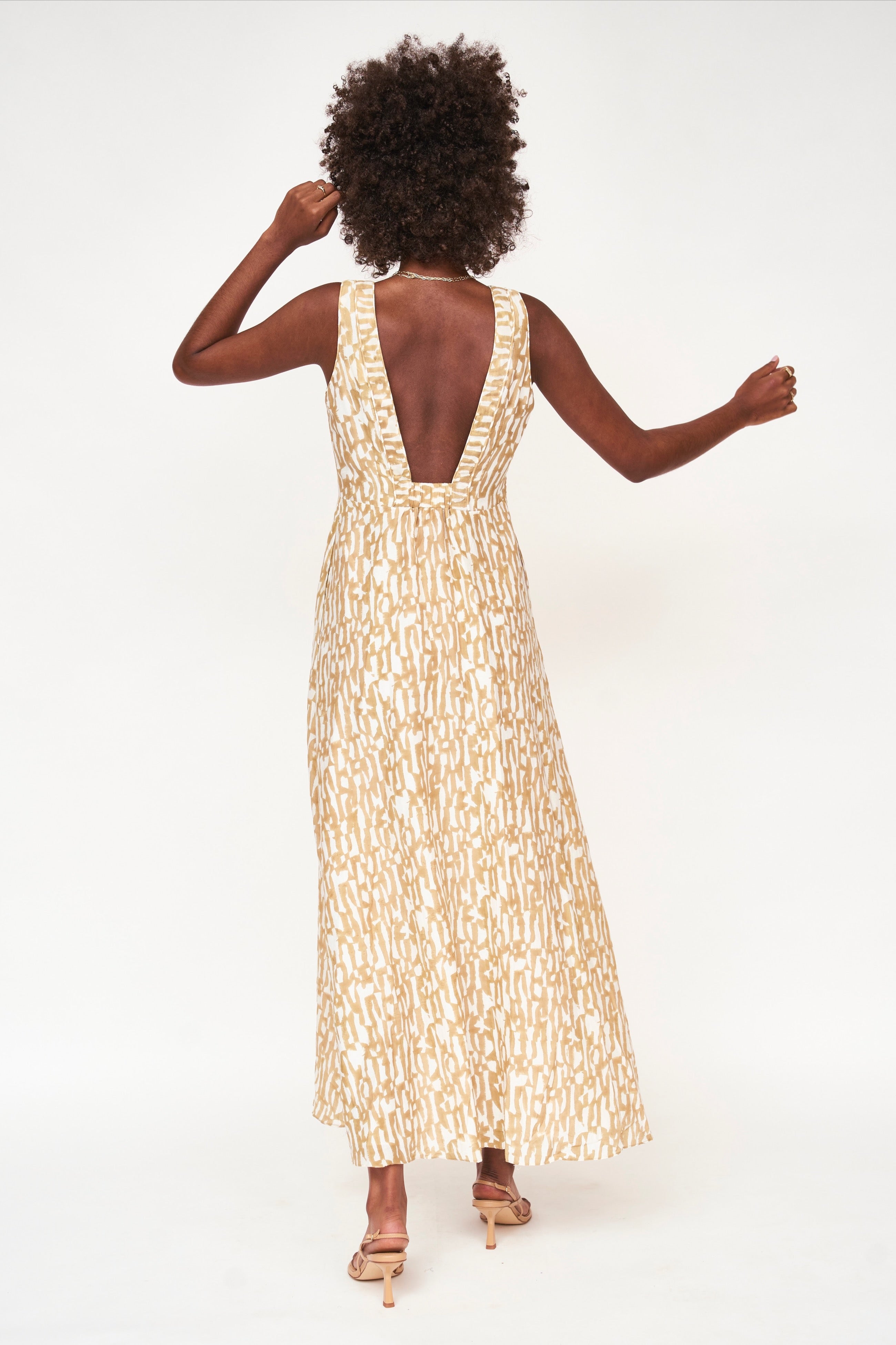 Girl wearing MIRTH women's v neck open back sleeveless cyprus long dress in driftwood brown print cotton silk