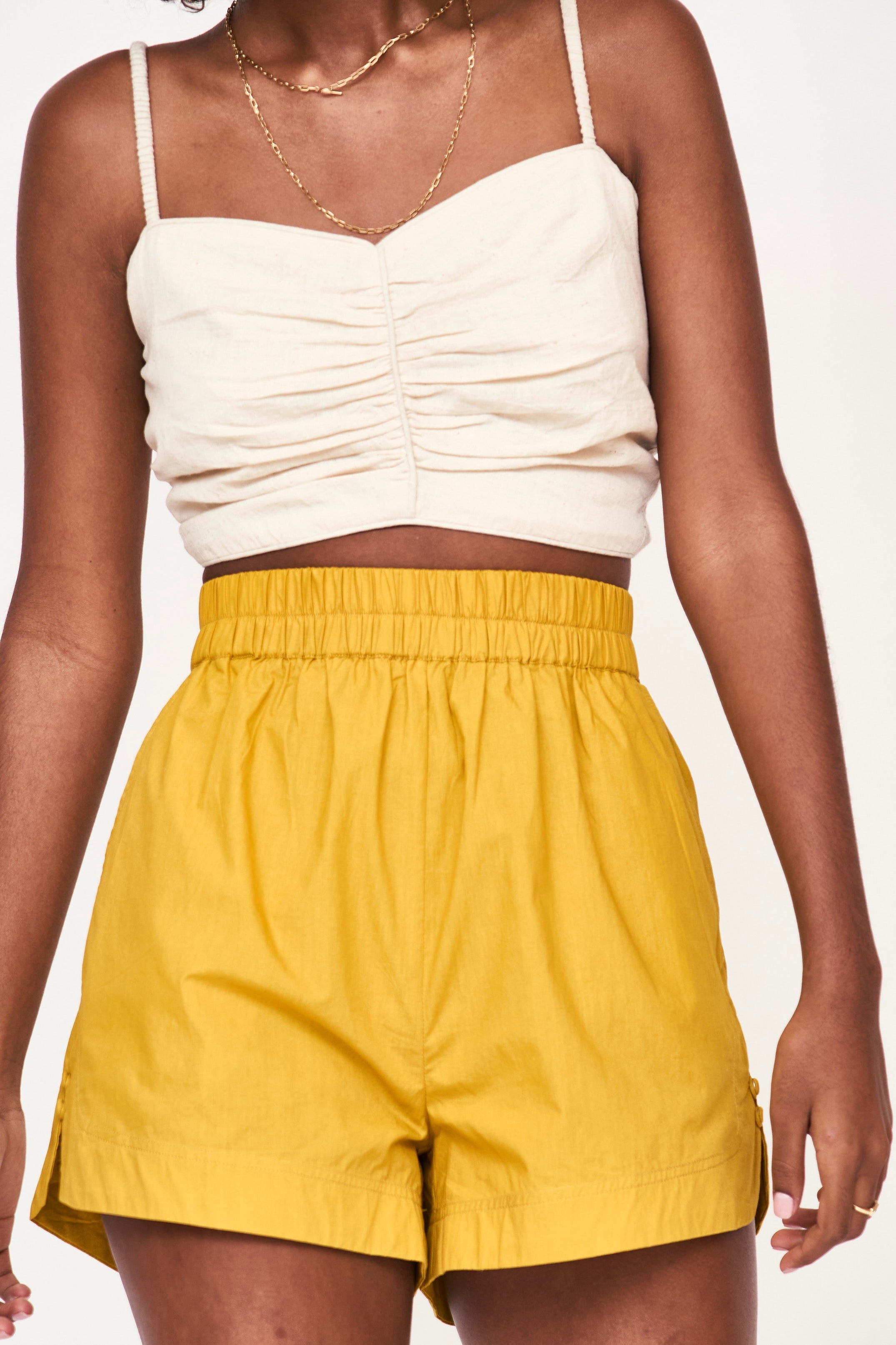 Girl wearing MIRTH women's tie back deia cropped sleeveless top in oatmeal beige cotton