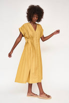 Girl wearing MIRTH women's midi v neck pleated korcula dress in gilded yellow cotton