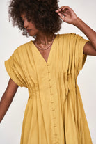 Girl wearing MIRTH women's midi v neck pleated korcula dress in gilded yellow cotton