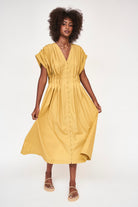 Girl wearing MIRTH women's midi v neck pleated korcula dress in gilded yellow cotton