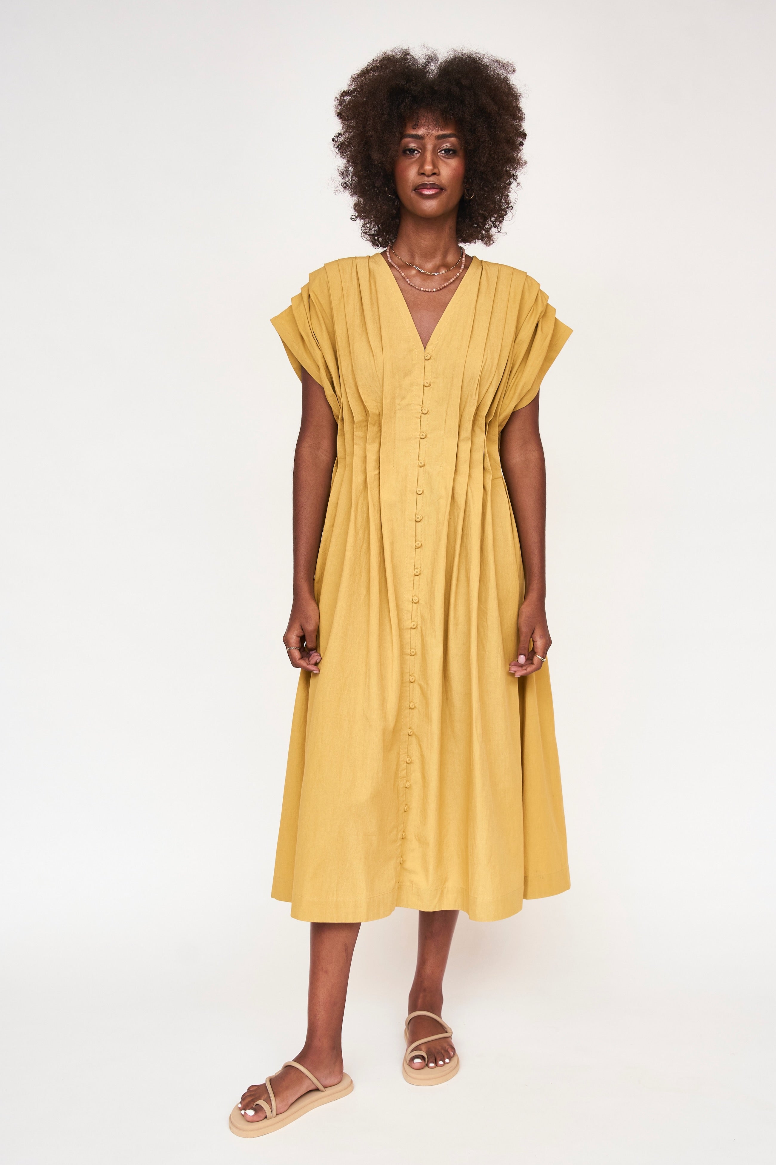 Girl wearing MIRTH women's midi v neck pleated korcula dress in gilded yellow cotton