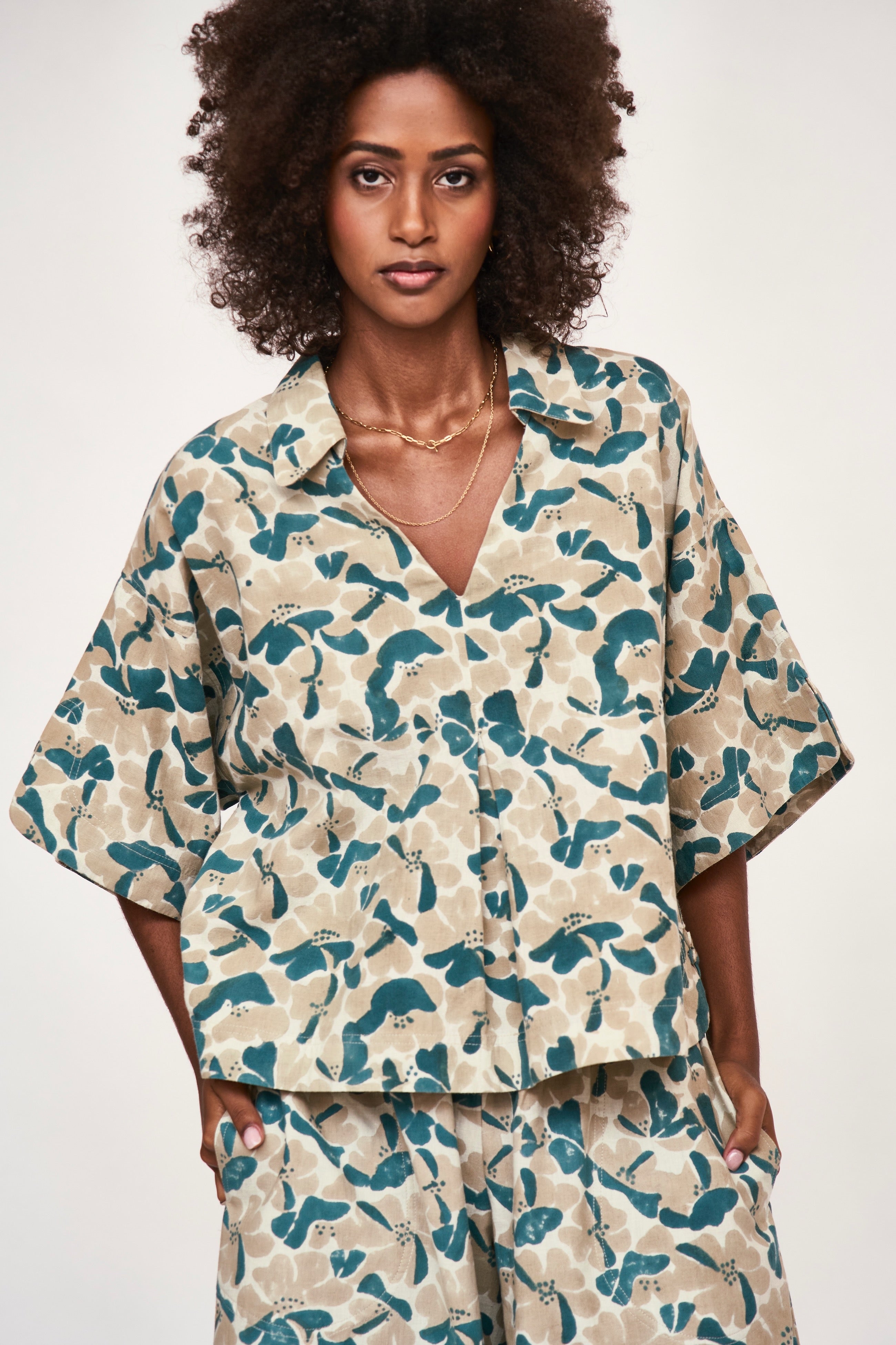 Girl wearing MIRTH women's v neck collared three quarter sleeve lanai top in plumeria blue floral print cotton