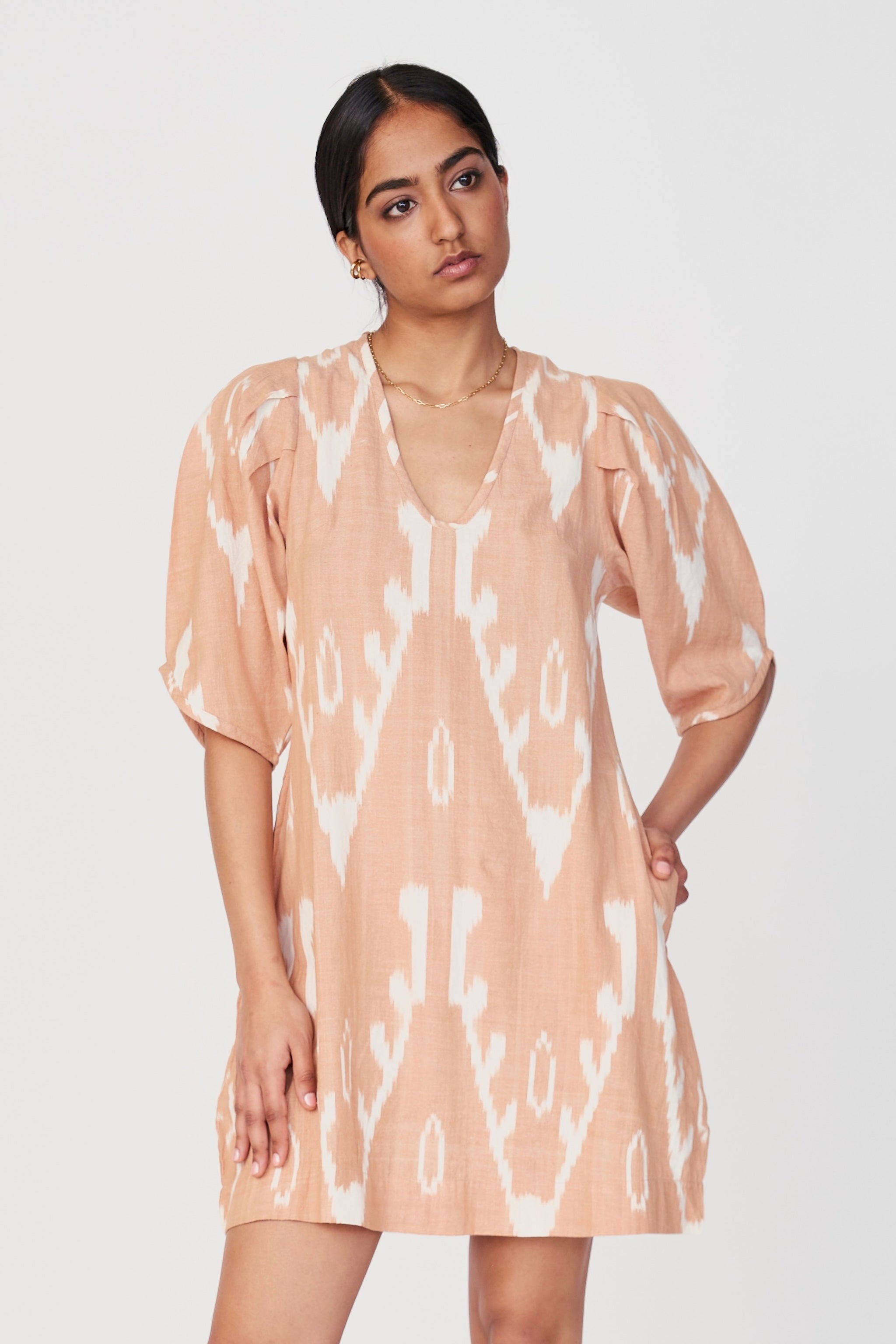 Girl wearing MIRTH women's puff sleeve v neck cassis short dress in conch ikat peach cotton