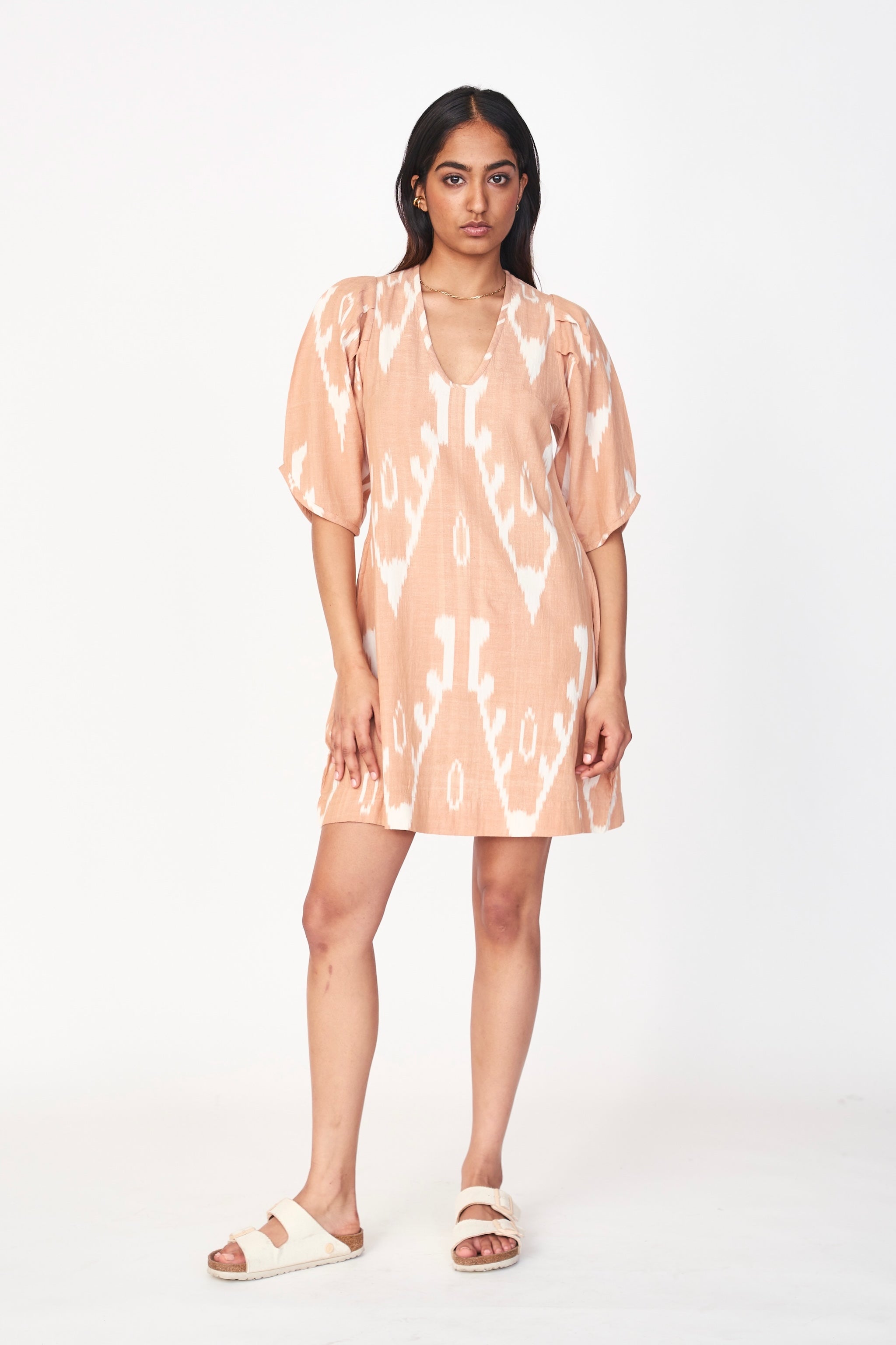 Girl wearing MIRTH women's puff sleeve v neck cassis short dress in conch ikat peach cotton