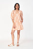 Girl wearing MIRTH women's puff sleeve v neck cassis short dress in conch ikat peach cotton