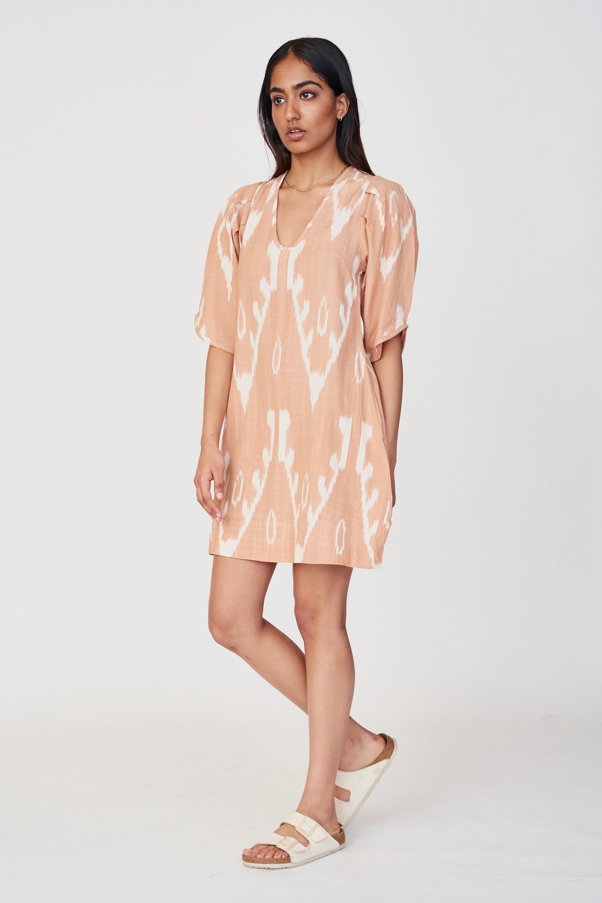 Girl wearing MIRTH women's puff sleeve v neck cassis short dress in conch ikat peach cotton