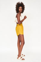 Girl wearing MIRTH women's wide leg elastic track shorts in gilded yellow cotton