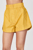 Girl wearing MIRTH women's wide leg elastic track shorts in gilded yellow cotton