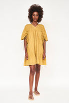 Girl wearing MIRTH women's v neck pleated pull string malta lined coverup short dress in gilded yellow cotton