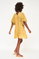 Girl wearing MIRTH women's v neck pleated pull string malta lined coverup short dress in gilded yellow cotton