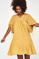 Girl wearing MIRTH women's v neck pleated pull string malta lined coverup short dress in gilded yellow cotton